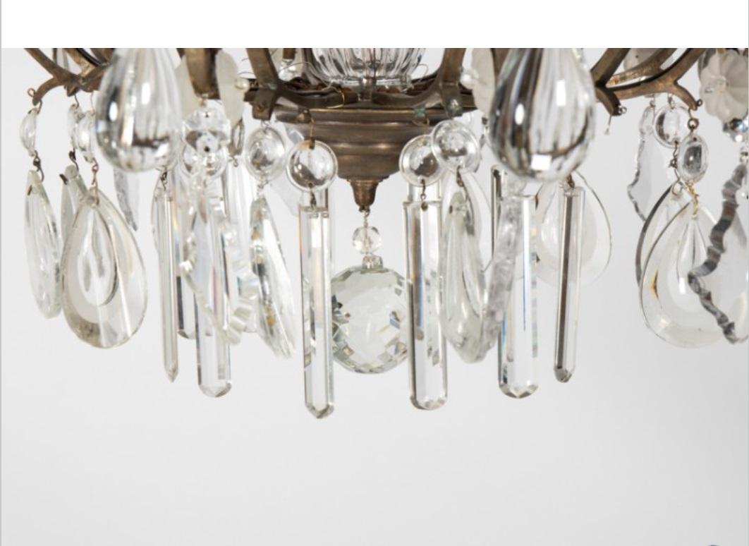 Marvelous antique crystal chandelier made in France circa 1900. Beautiful brass scrollwork is embellished with rectangular cut crystal glass and elaborate crystal finials. A romantic, glittering light fixture that adds old world charm to any room.