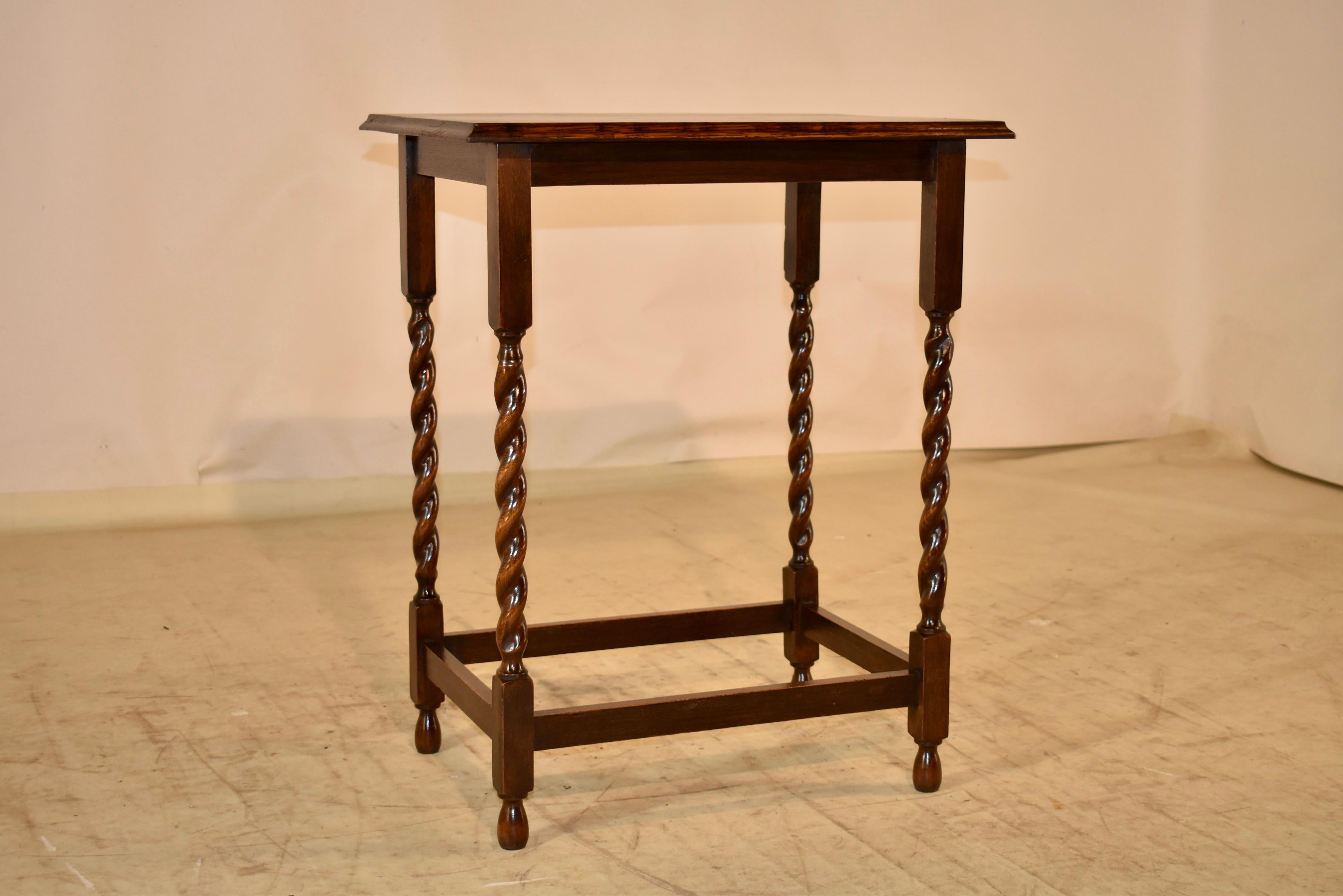 Circa 1900-1910 oak occasional or side table from England.  The top has magnificent graining, and is surrounded by an elegant beveled edge.  This follows down to a simple apron and the table is supported on hand turned barley twist legs, joined by