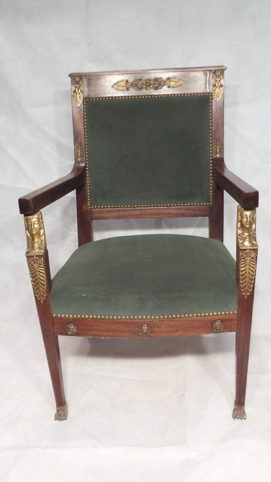 A wonderful Egyptian revival antique chair in mahogany originating from France in the later period of the 19th century. This lovely chair is complimented by ormolu mounts in the form of Egyptian ladies face on the arms and decorative ormolu frets on