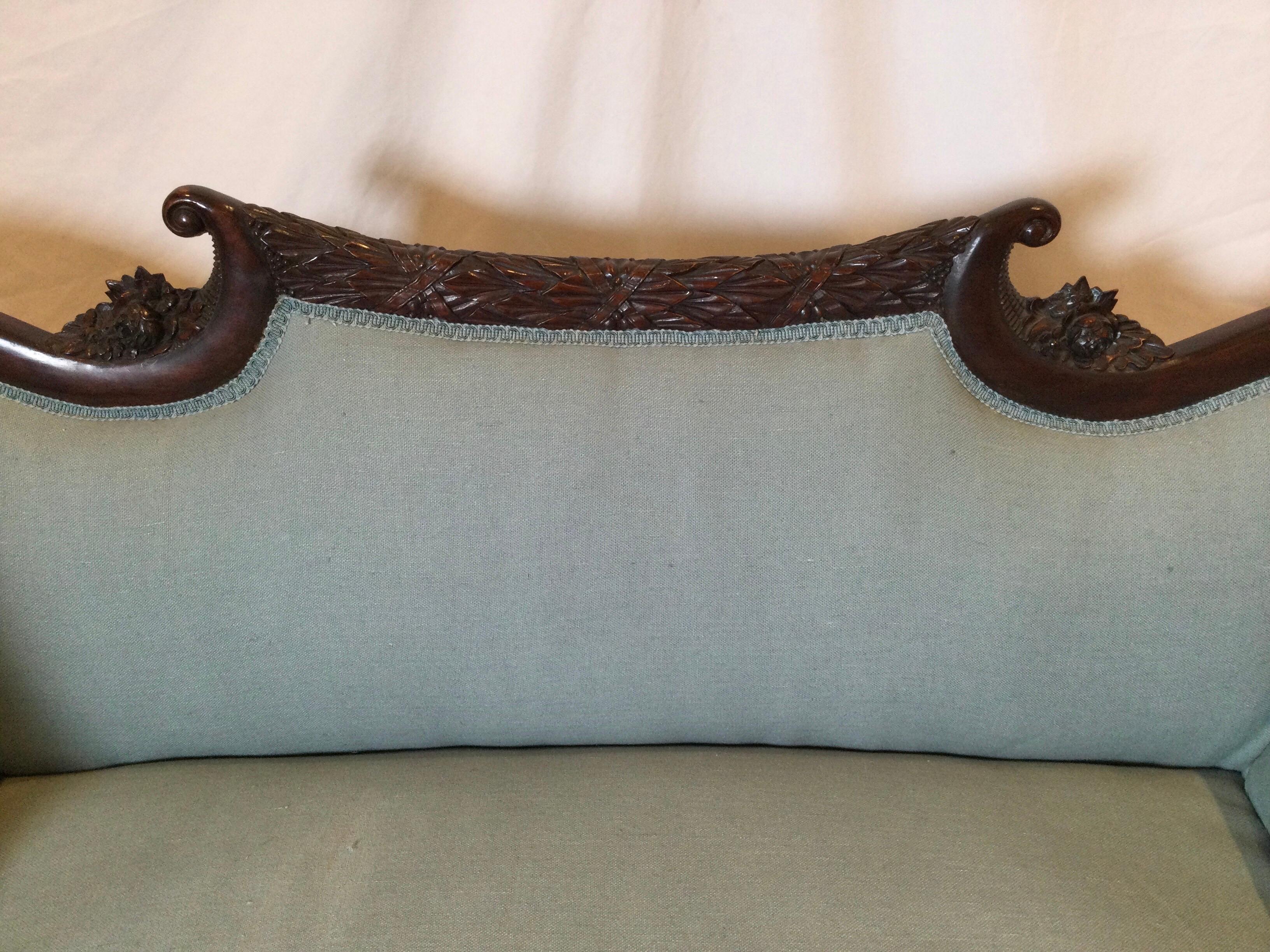 Graceful hand carved empire settee with new linen blend fabric. The beautifully carved dark mahogany frame with paw feet, attached back and seat, newly recovered. The medium grey blue fabric can easily be changed if desired. 

Measures: 54