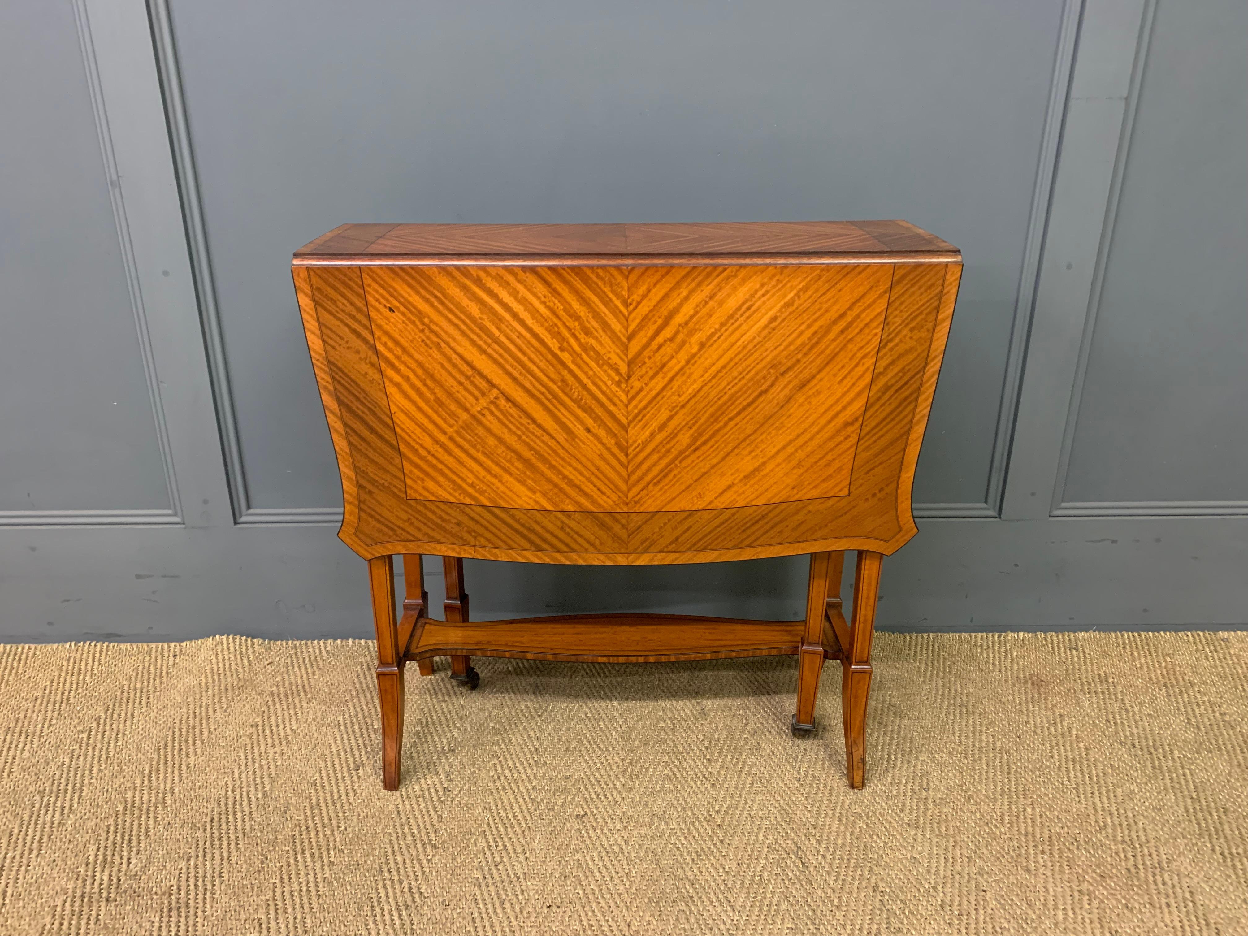 Circa 1900 Edwardian period Sutherland Table, English. Satinwood with tortoise shaped top. The diamond bookmatched veneer ever expanding out is spectacular. Ebony tracery. Square, tapered, flared, ebony inlaid satinwood legs. Shaped stretcher shelf.