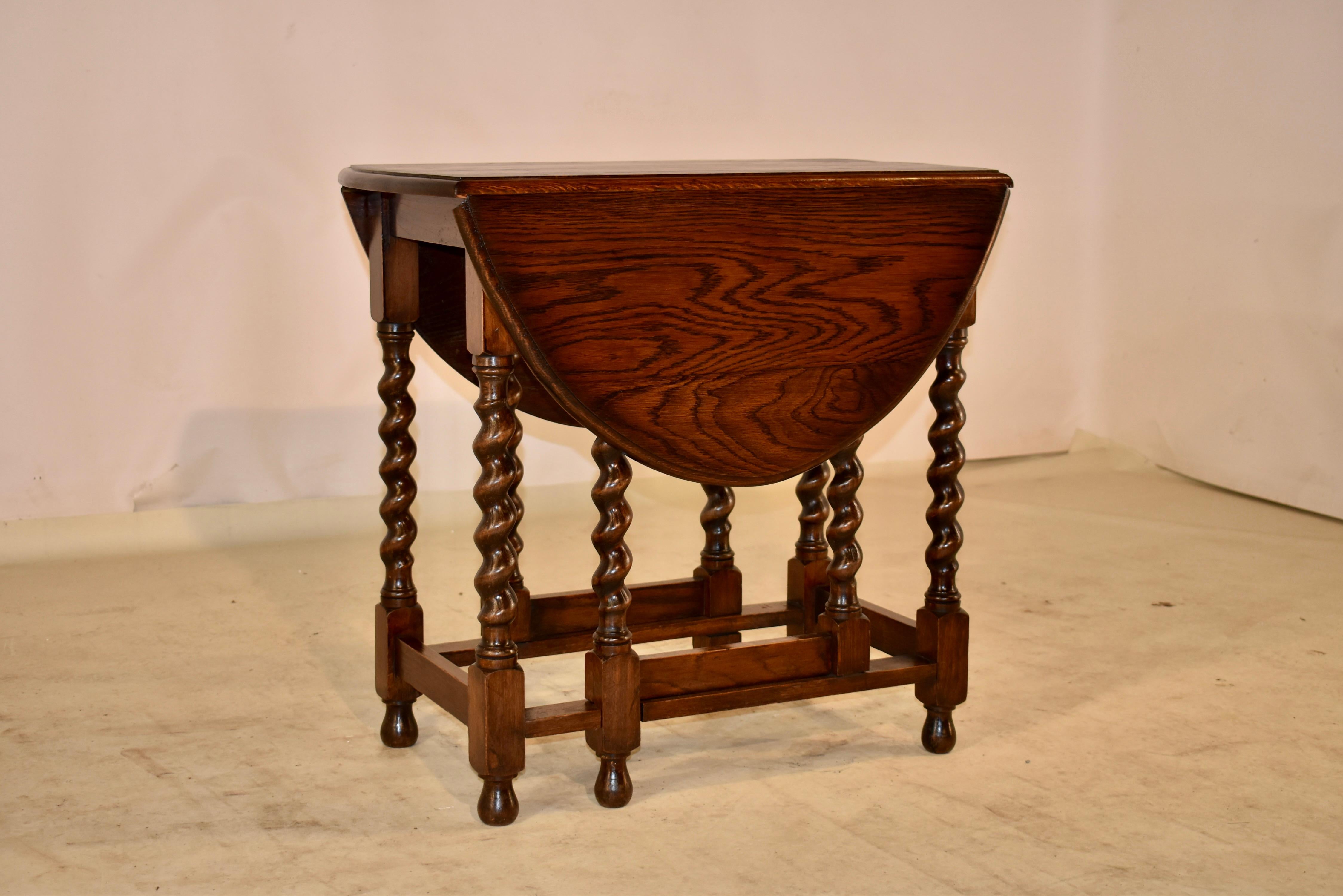 Circa 1900 oak gate leg table from England with a beveled edge around the vividly figured top, following down to simple aprons. the table is supported on hand turned barley twist legs, joined by simple stretchers and raised on hand turned feet. The