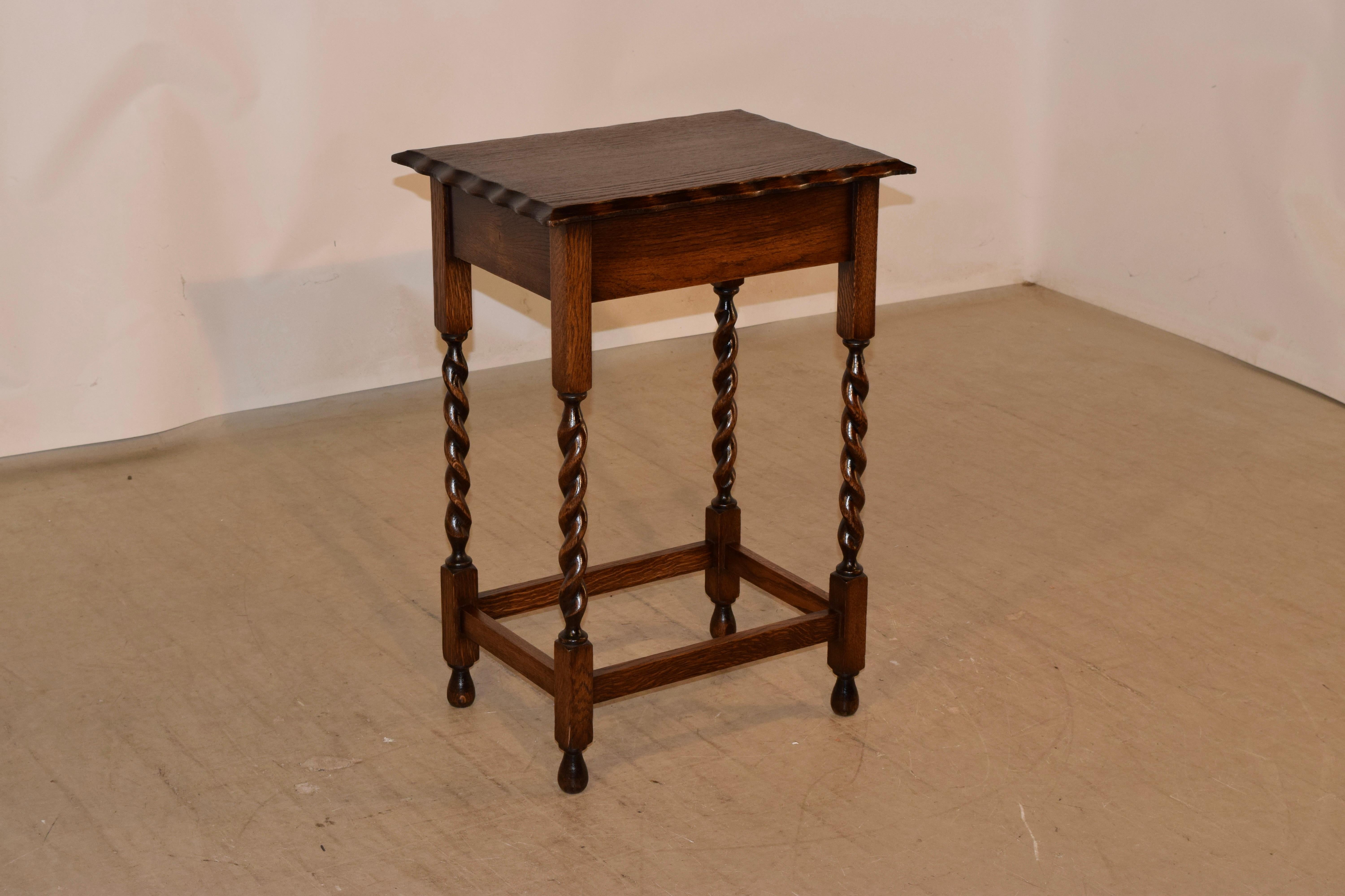 Circa 1900 Edwardian oak side table from England with a beveled and scalloped edge around the top, following down to a simple apron and supported on hand turned barley twist legs, joined by simple stretchers and raised on hand turned feet.