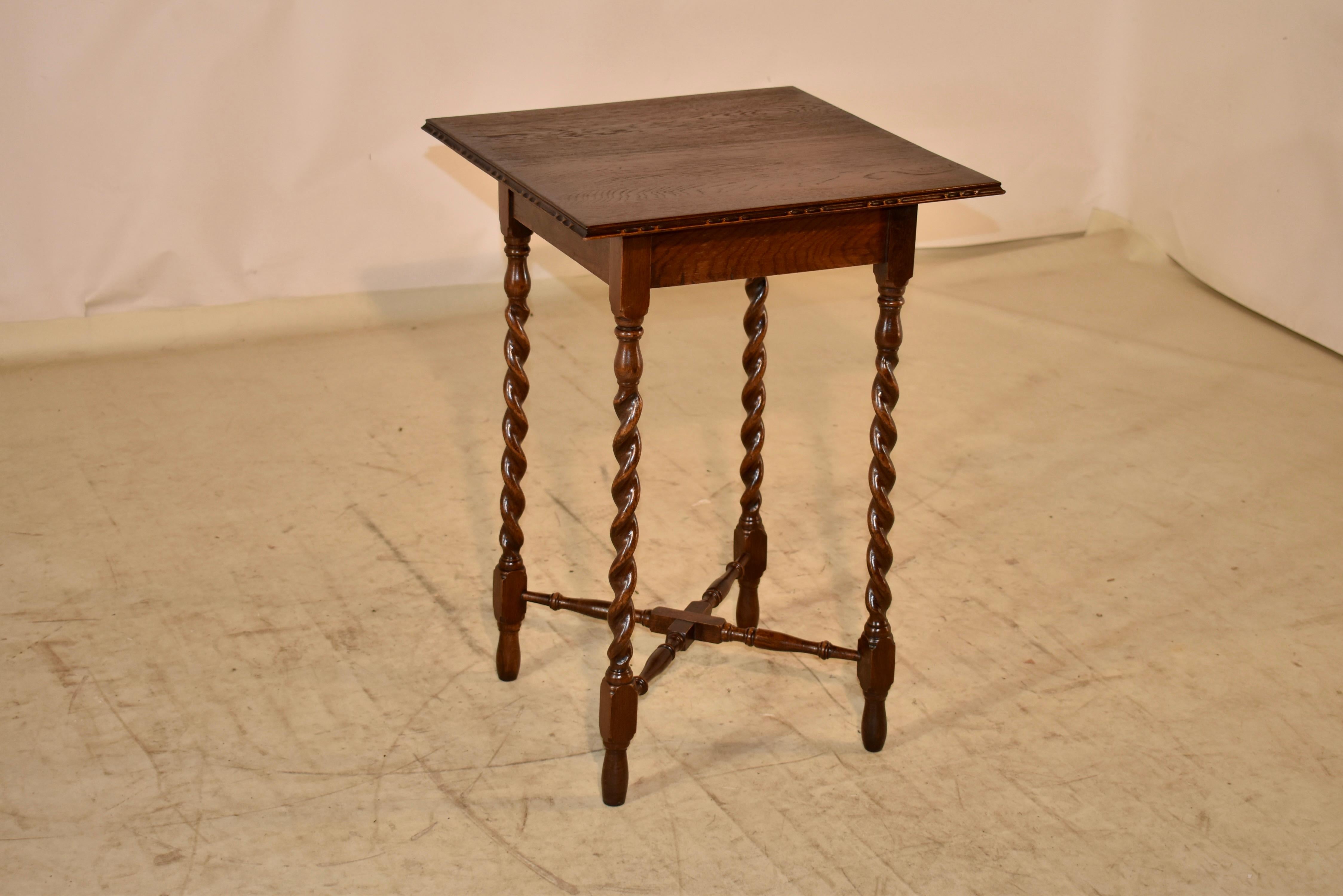 circa 1900 Edwardian oak side table from England. The top has a beveled and carved decorated edge, following down to a simple apron. The table is supported on hand turned barley twist legs, joined by hand turned cross stretchers and raised on hand