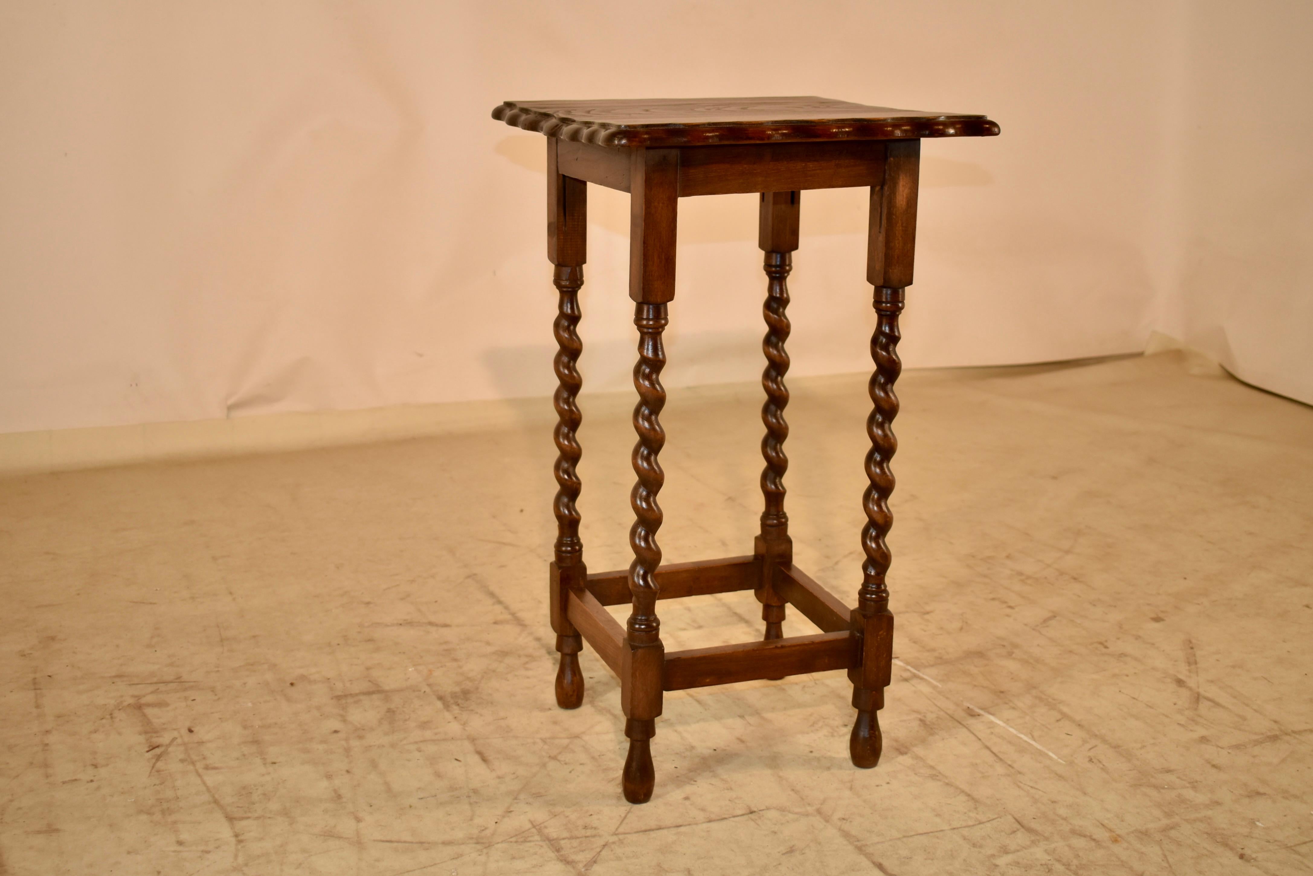 Circa 1900 period Edwardian oak side table from England.  The top has lovely graining, and is surrounded by a beveled and scalloped edge.  The top follows down to a simple apron and is supported on hand turned barley twist legs, joined by simple