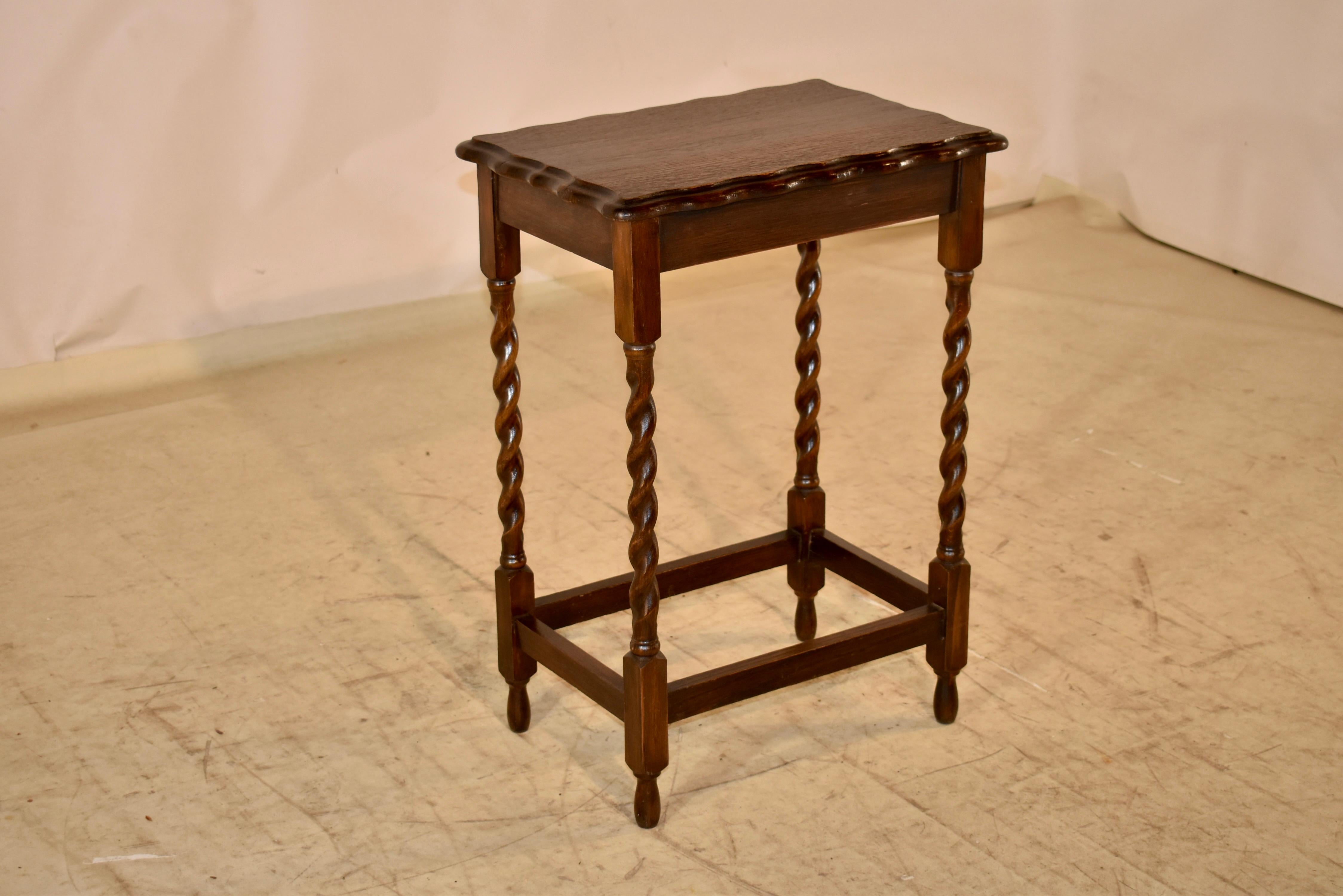 Circa 1900 English oak side table with a beveled and scalloped edge, following down to a simple apron and supported on hand turned barley twist legs, joined by simple stretchers.  The table is raised on hand turned feet.