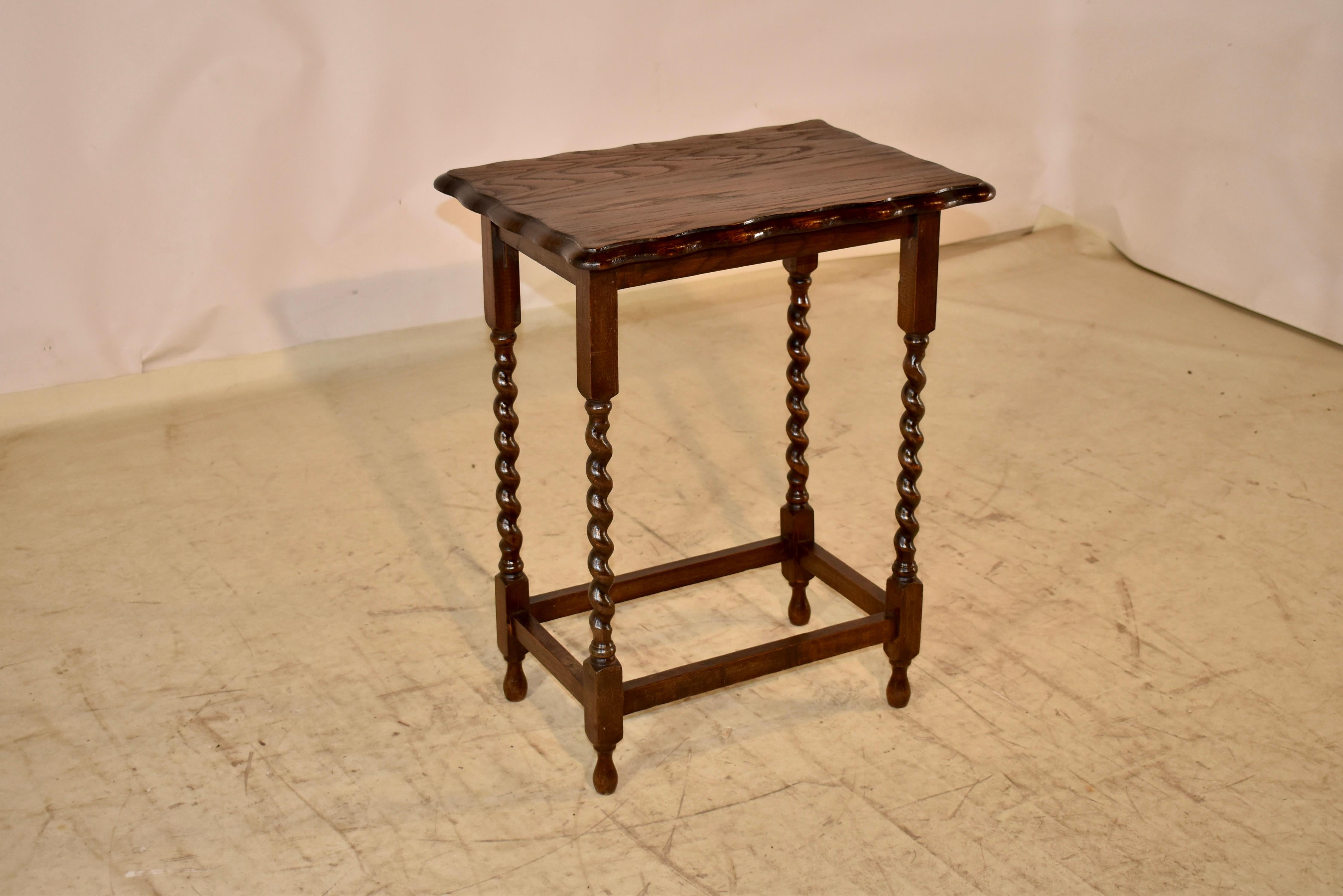 Mesa auxiliar de época eduardiana de roble procedente de Inglaterra.  Hay un borde biselado y festoneado, que rodea una encimera maravillosamente veteada, siguiendo hasta un sencillo delantal.  La mesa se apoya en patas torneadas a mano, unidas por