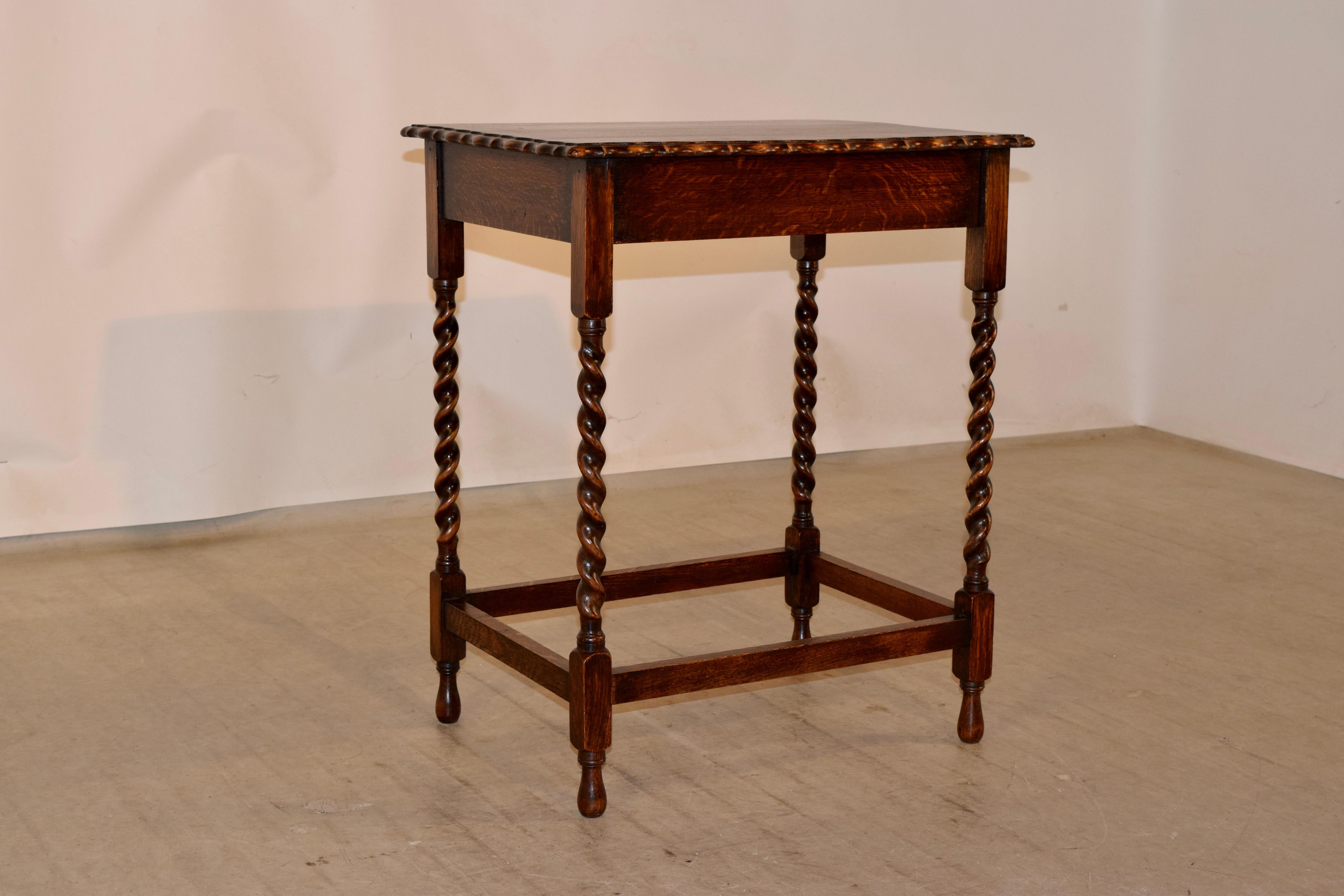 Edwardian oak side table from England with a scalloped and bevelled edge around the top, over a simple apron and supported on hand turned barley twist legs, joined by simple stretchers and raised on hand turned feet.