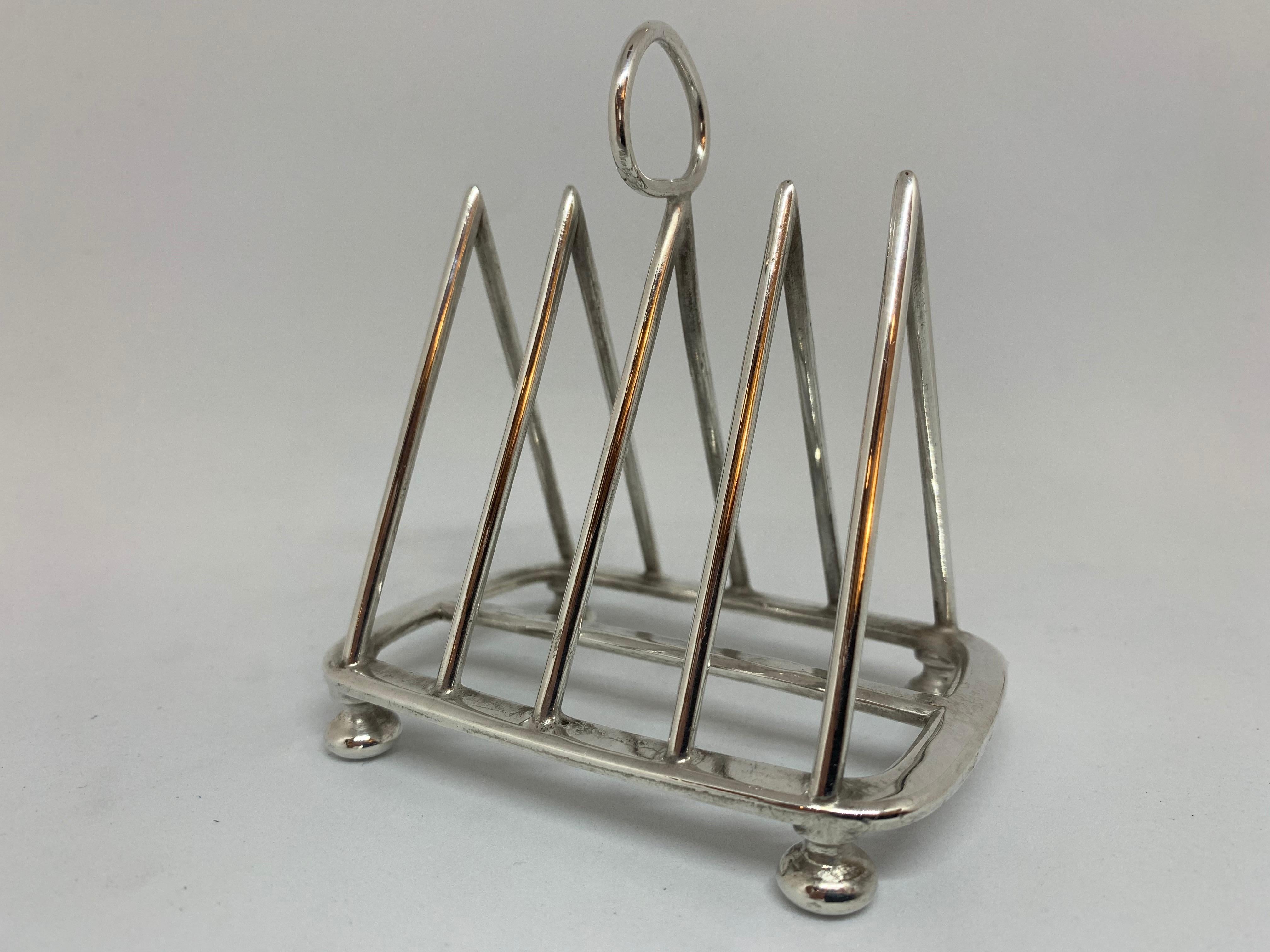 An English silver plate toast rack in a triangular pyramid shape divided into four sections with room for four slices of toast, circa 1900. Made in Sheffield by Walker & Hall. Hallmarked on the base.

Measres: H 9 1/2 cm, D 6 cm, W 9cm.