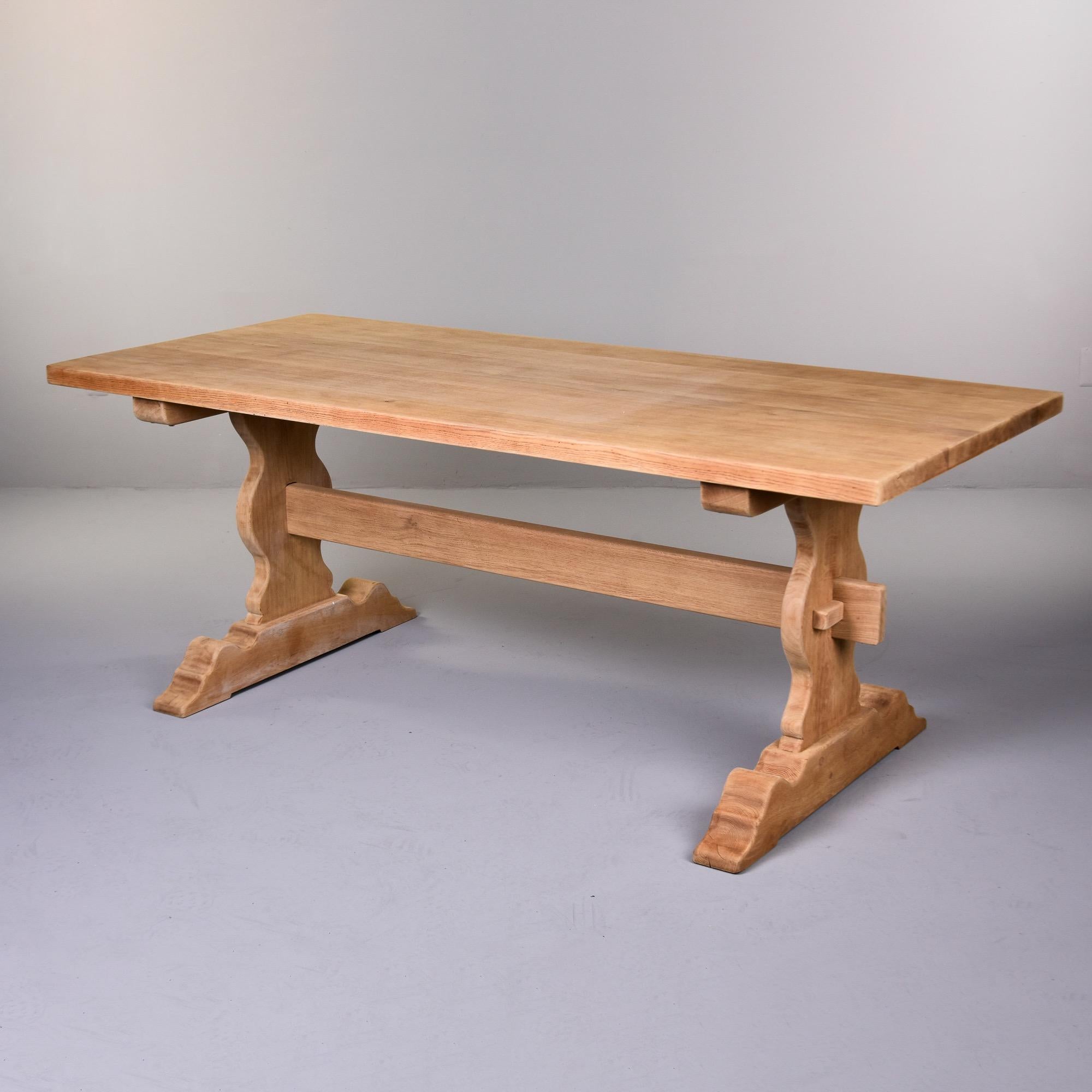 Found in France, this circa 1900 French oak farm trestle table has a bare finish and has been sanded smooth.  Classic trestle-style table is structurally sturdy with mortise and tenon construction. Scattered visible age and honest wear to table top