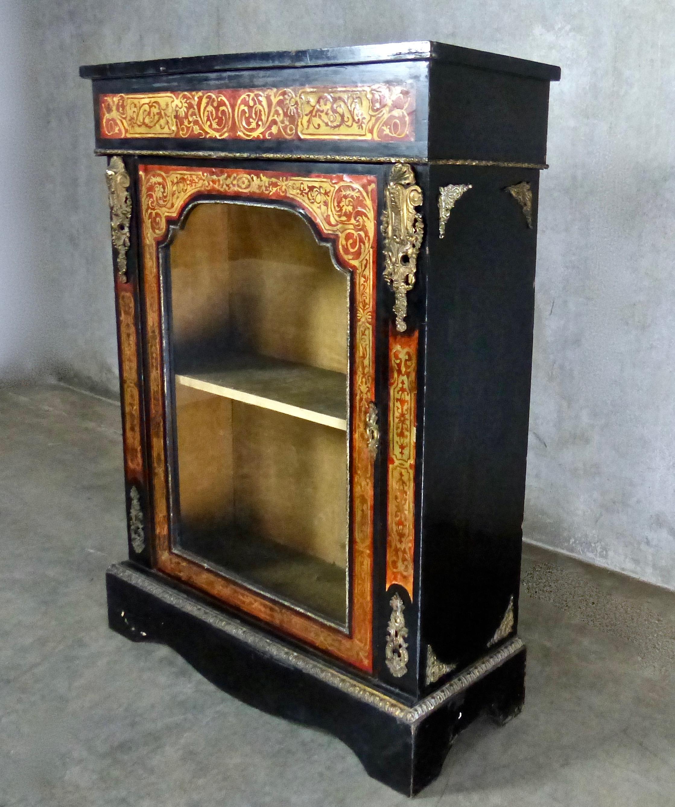 A hand painted, red-and-black lacquered cabinet with ornate, Ormolu accents (gilded, cast metal). Beautifully detailed throughout, with its high gloss finish intact. Display shelves behind glass doors. A wonderful piece in original