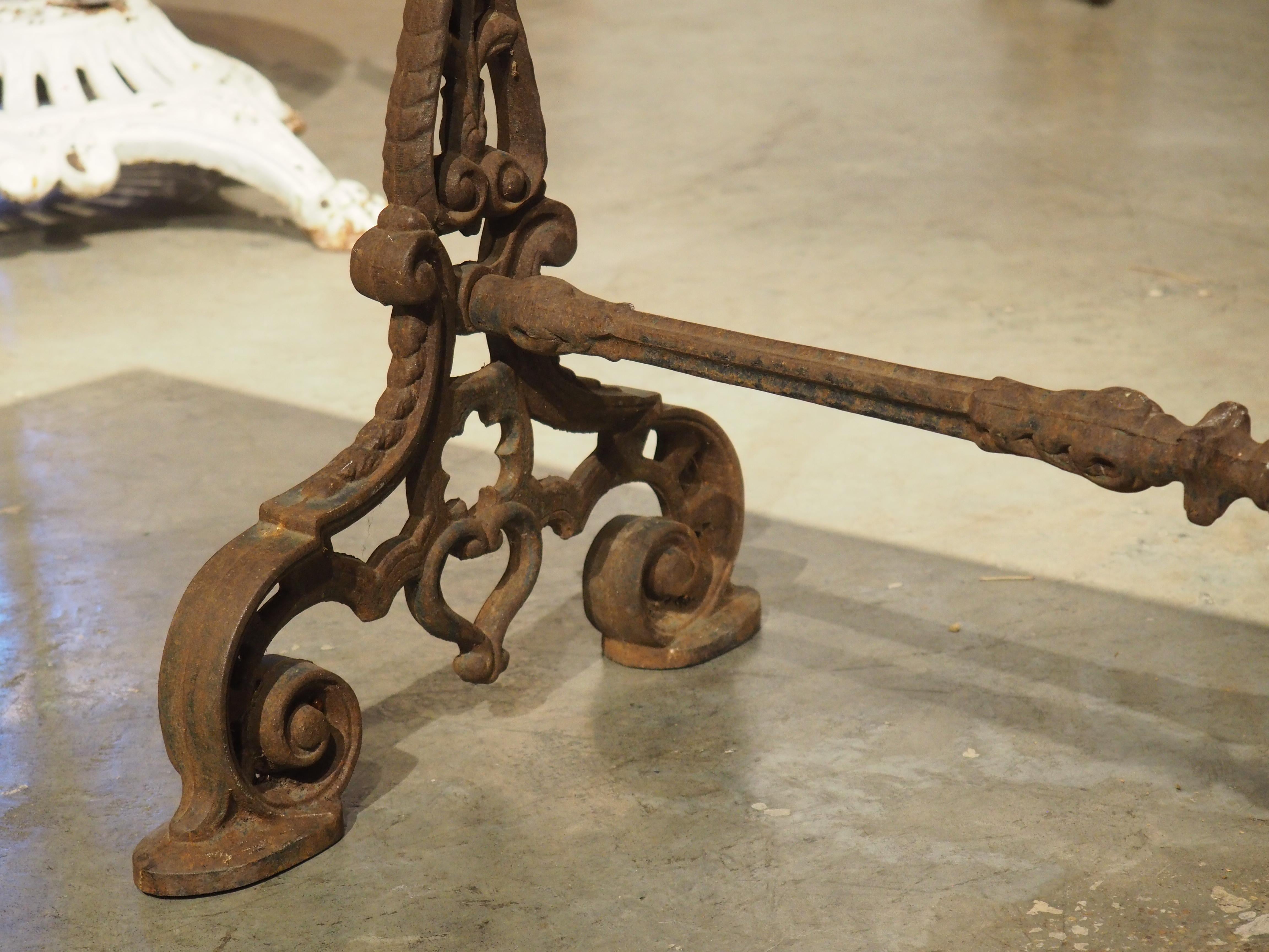 Charmante table de bistrot française datant d'environ 1900. La base en fonte présente des motifs de feuillage et une patine bien oxydée sur la finition noire d'origine. Les deux pieds à volutes sont reliés par une tige cylindrique avec des coupelles
