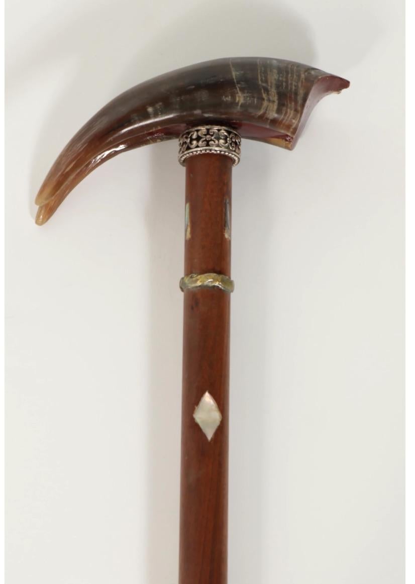This is a beautiful Late 19th-early 20th century walking stick (cane) with an exquisite shaped Horn handle with a decorative repousse sterling silver collar with Mother of Pearl inlay and a brass second collar- on a hardwood mount with rubber end