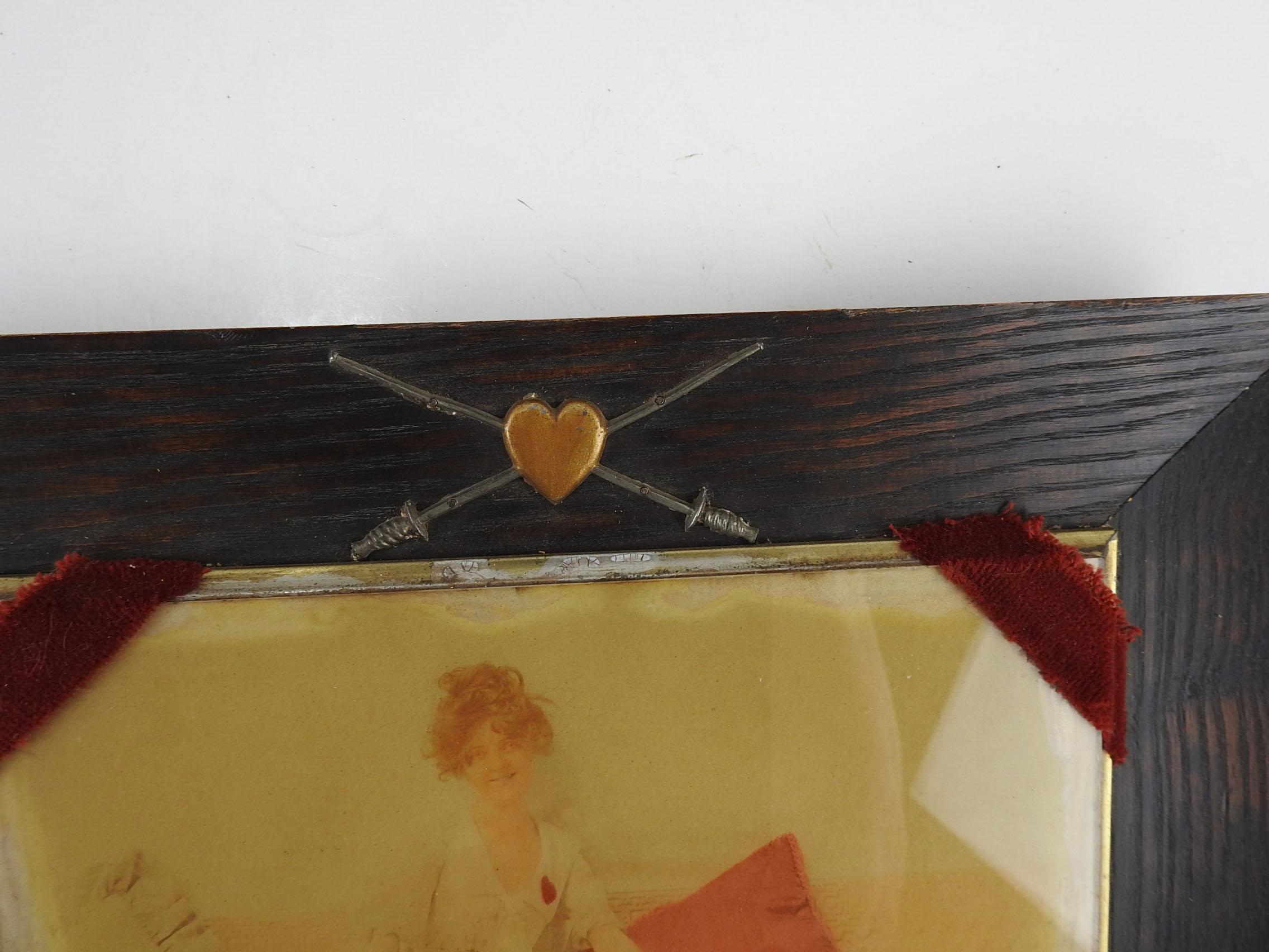 Circa 1900 fencing themed photograph of woman in fencing garb with red heart holding an epee.  Tinted red pillow and heart, original oak frame with heart and crossed fencing foils.  Photo is under glass, mounted on top of frame with burgundy velvet