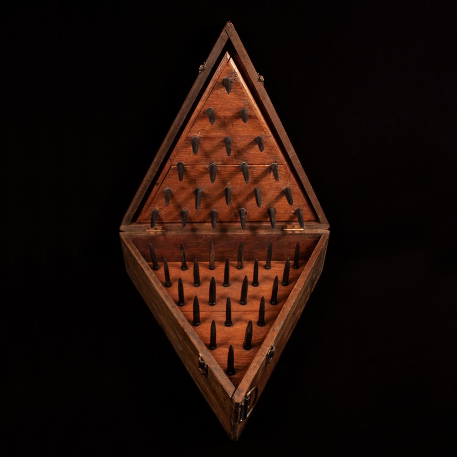 A triangular wooden case contains two separate wooden triangles, one studded with iron spikes and the other with rubber facsimiles. Apparently, during the initiation of new members, candidates were blindfolded after being shown a triangular chair
