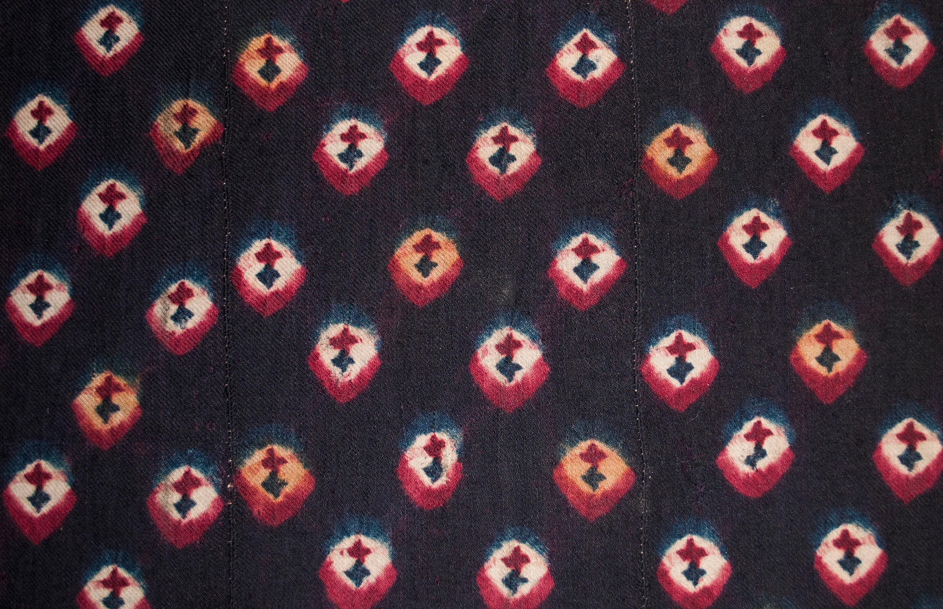 Gefärbte Tafel aus Tibet, um 1900.

Diese Art von krawattengefärbter Wolle, die von tibetischen Nomaden auf dem Rückenriemenwebstuhl gewebt wurde, wurde traditionell für Pferdedecken, Sitzmatten oder als Besatz für Satteldecken und Schlafteppiche