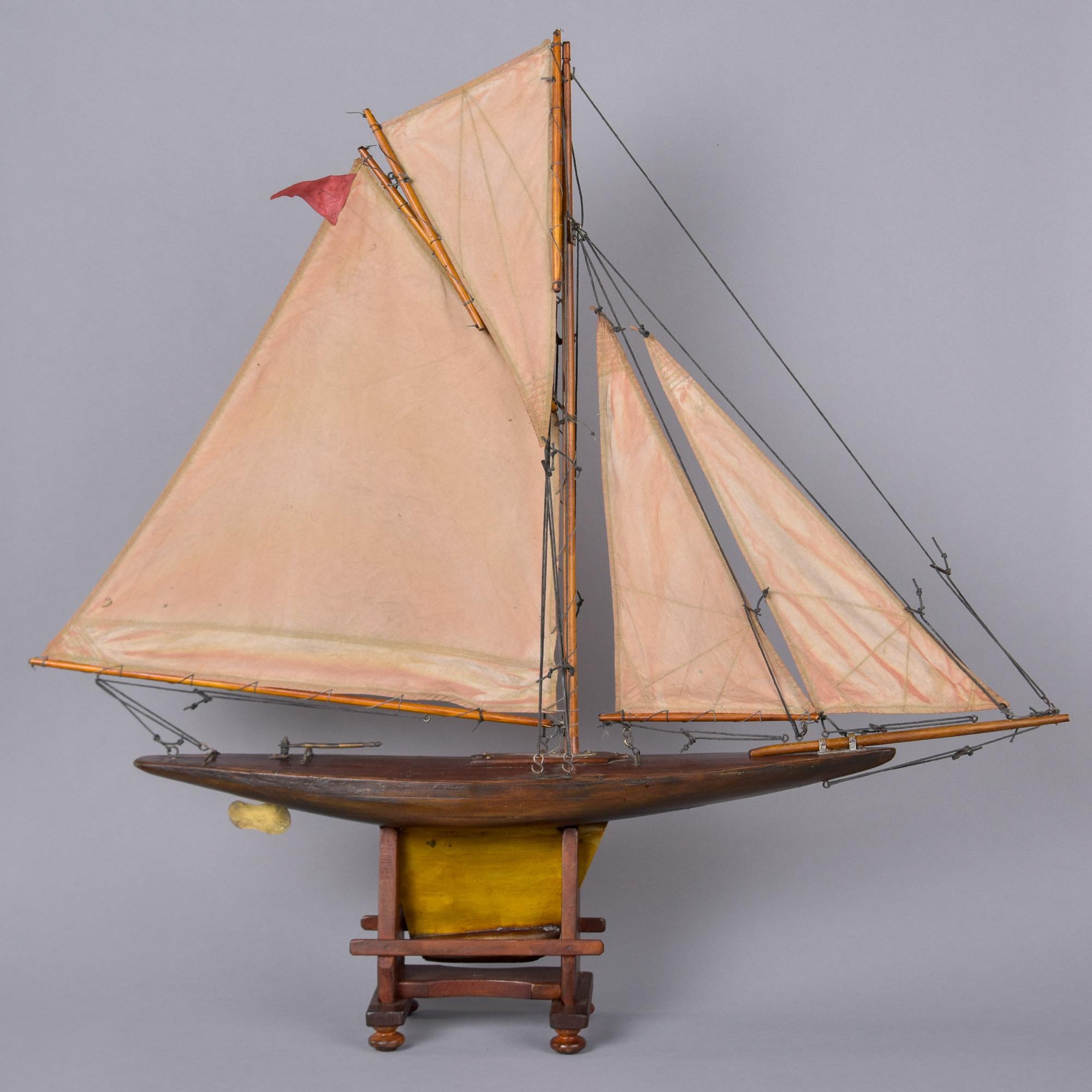 Dieses in England gefundene große Teichboot mit Ständer stammt aus dem Jahr 1910. Dieses handgefertigte antike Teichboot verfügt über die originalen vier Stoffsegel und die Takelage, das Ruder und die Beschläge aus Messing, den geschnitzten Rumpf