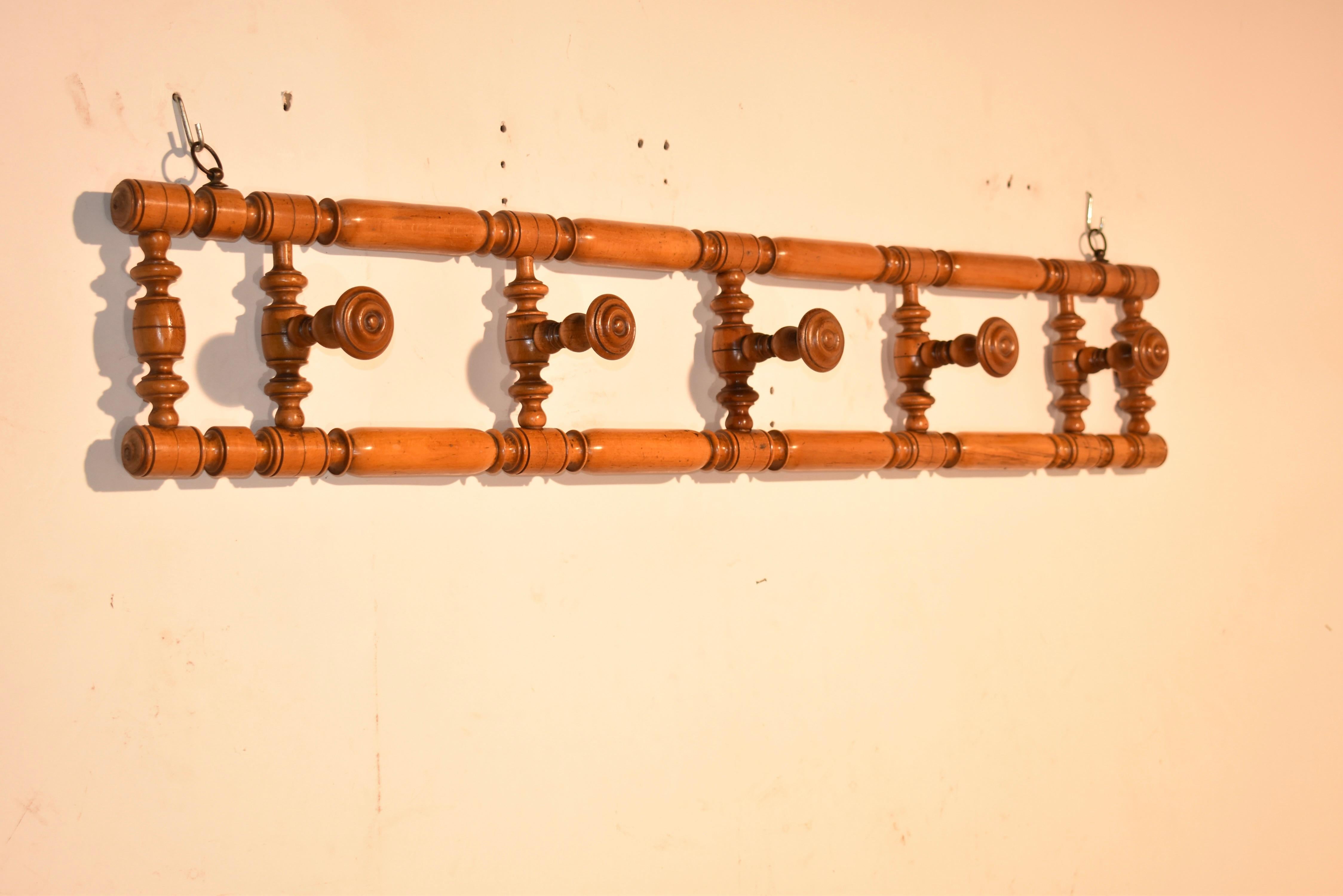Cherry hat rack from France, circa 1910. The rack is lovely and is made from a hand turned frame, the sides of which are joined by seven turned spindles. Five of the spindles have turned pegs, which are wonderfully detailed. This is a wonderful