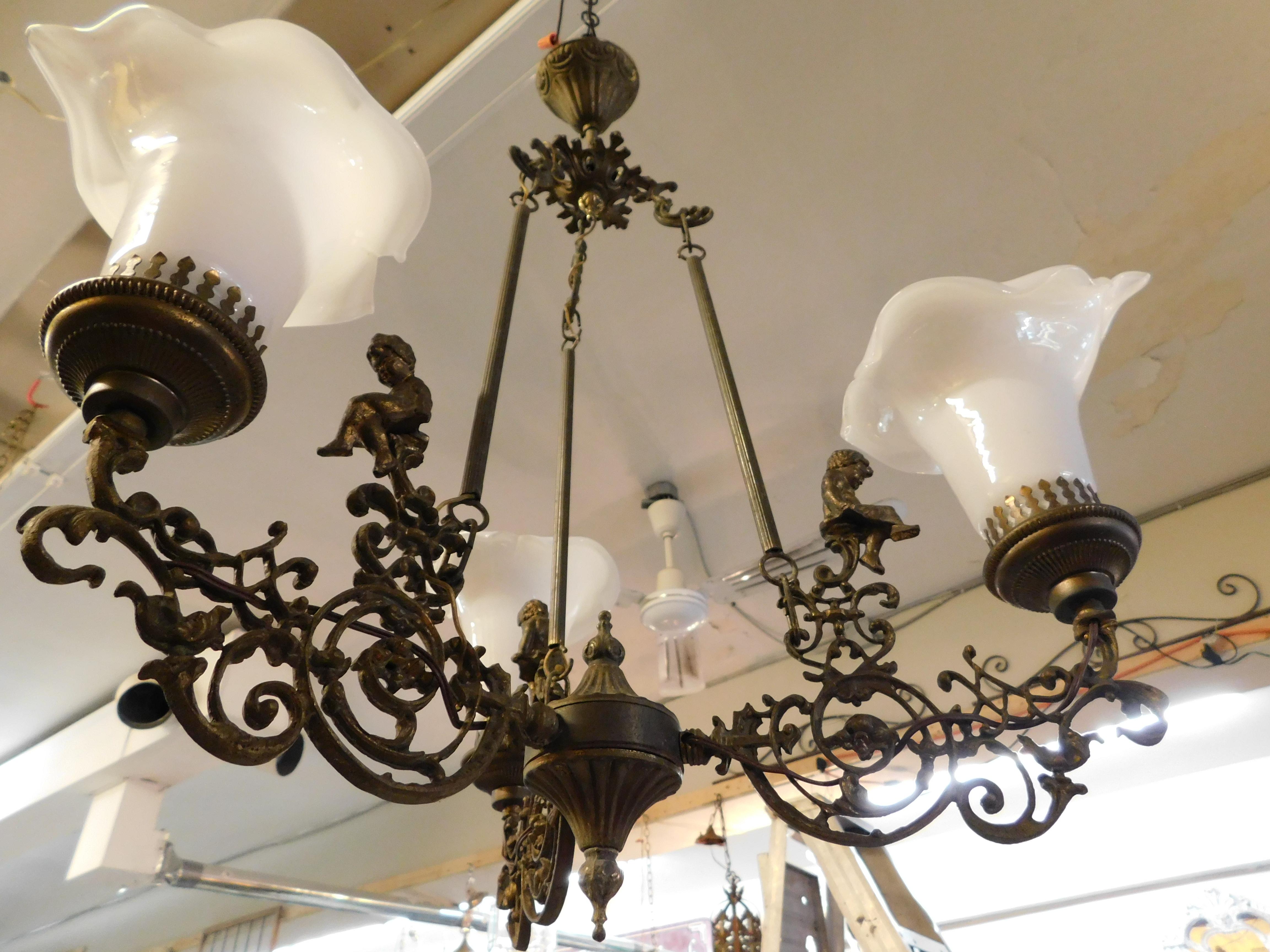 Early 20th century French bronze figural chandelier with 3 cherubs or Putto. Three hand blown milk glass shades have been replaced with newer versions. Bulbs are European thread, 3 bulbs included.

The more commonly found form putti is the plural