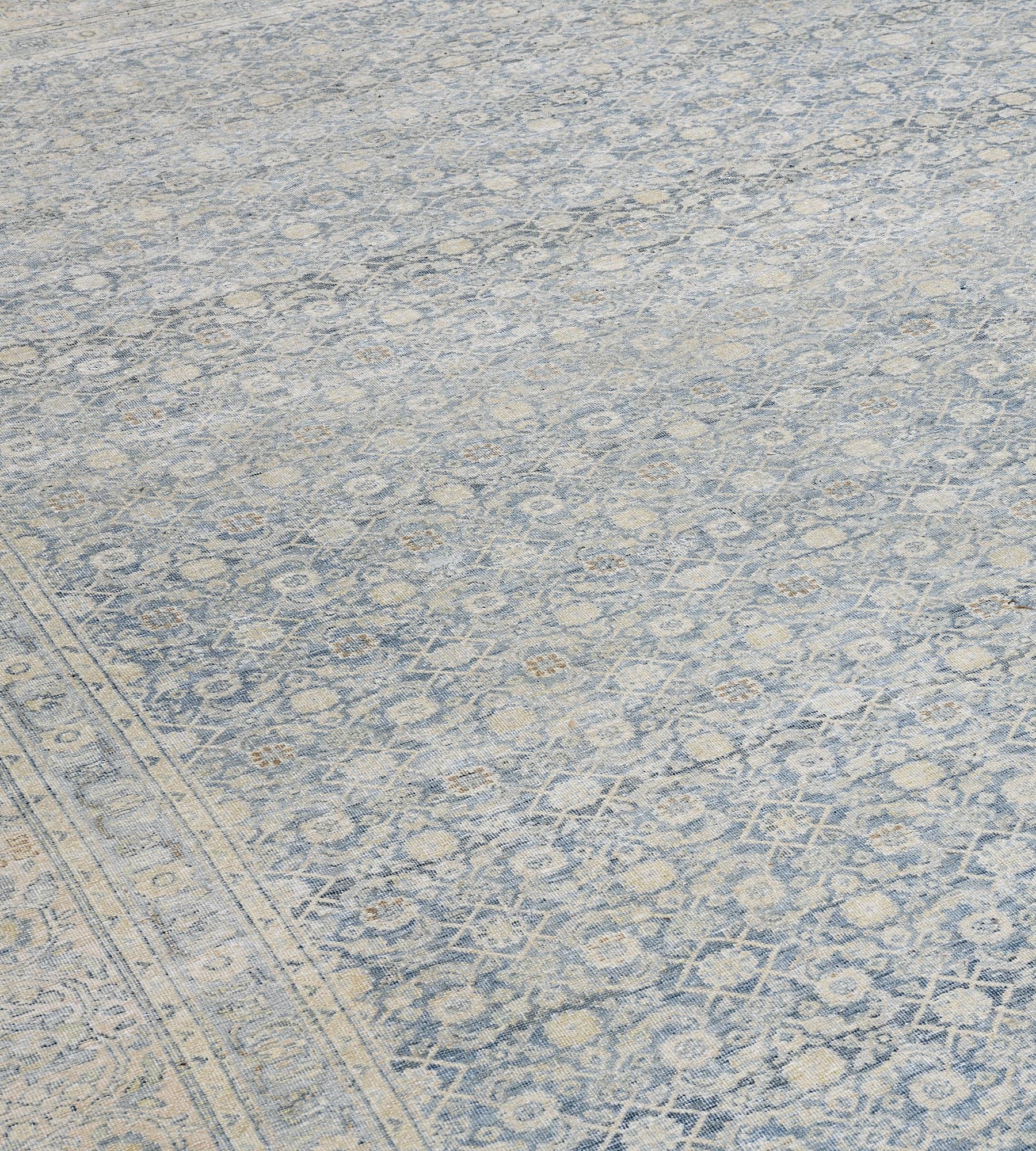Ce tapis Tabriz persan ancien, vers 1910, présente un champ bleu indigo nuancé avec un délicat motif herati jaune sable, dans une bordure jaune sable avec une vigne sinueuse à enroulement feuillu reliant des palmettes et des tiges fleuries entre des