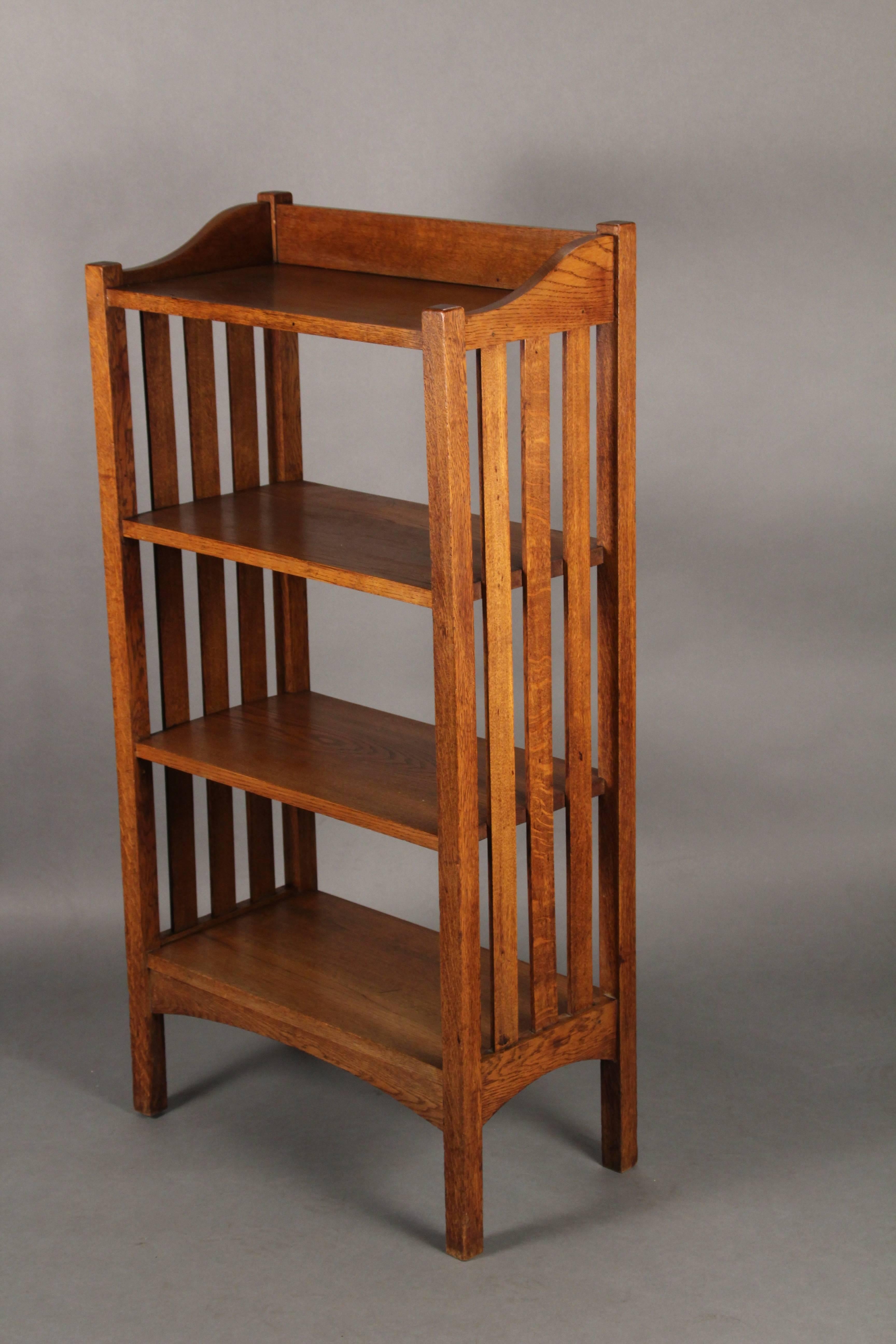 Oak bookcase with side slats, circa 1910. Arched apron. Unsigned.