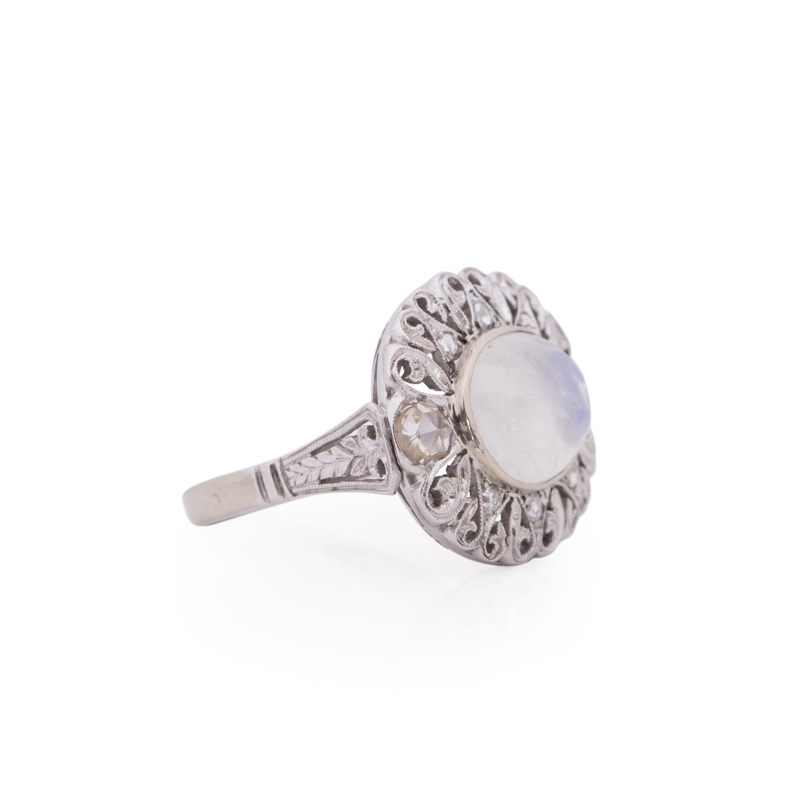Here we have a breathtaking 5 carat iridescent Moonstone sitting in a elegantly crafted 18K white gold mount. The filigree detailed halo around the moonstone has two vibrant rose cut diamonds on either side, and accenting those beauties are 6