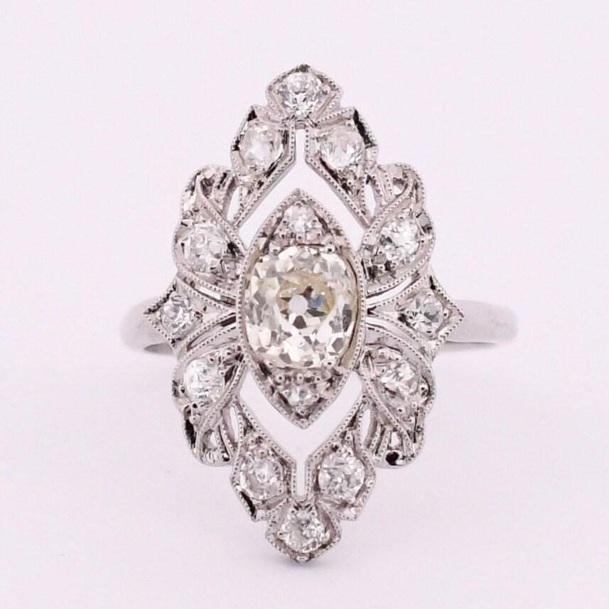 Presenting a truly captivating Edwardian marvel, this shield ring is a masterpiece crafted in platinum, showcasing exquisite detailing that evokes awe. From its delicate lace-like openwork to the dainty milgrain adorning each edge, every element has