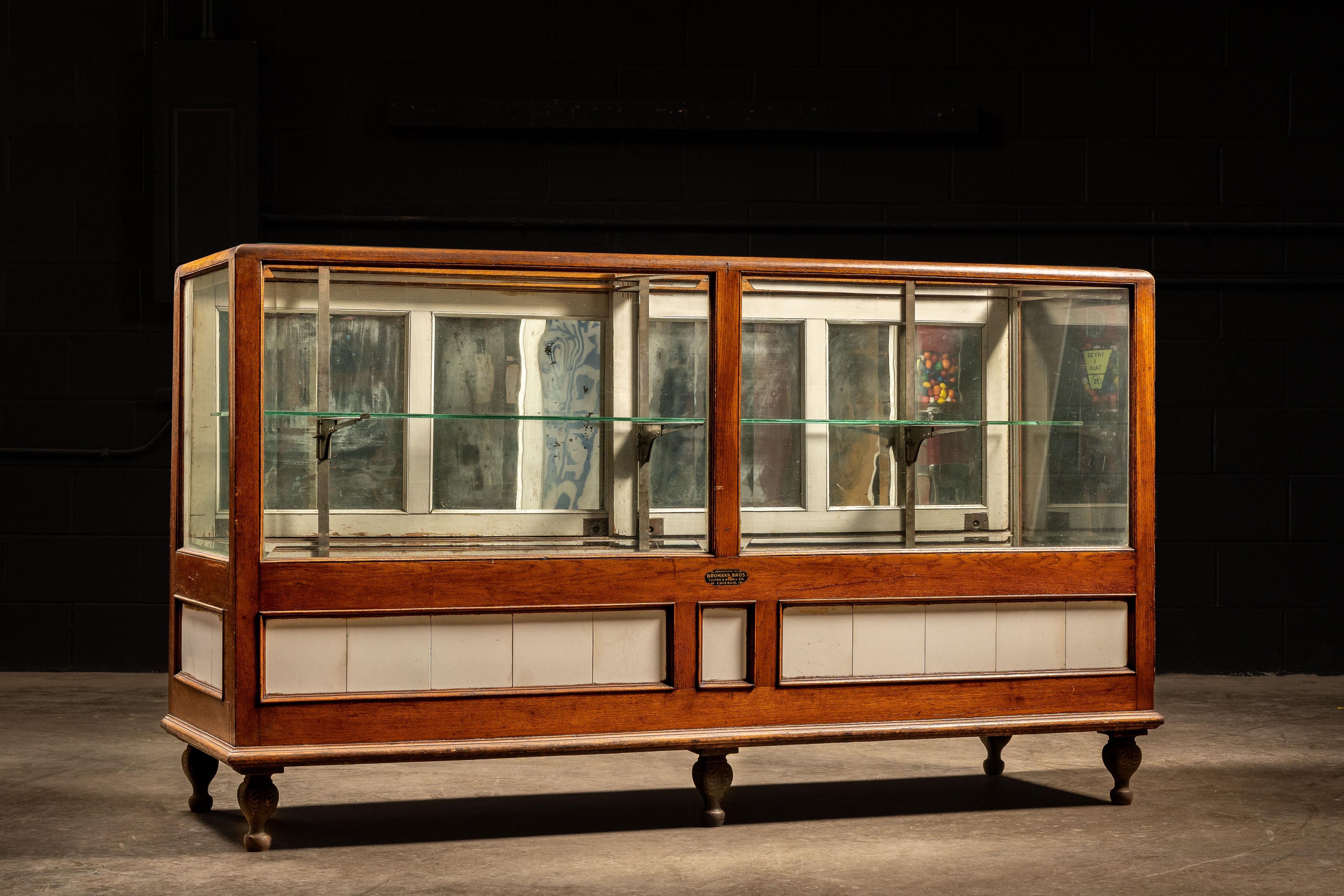 c. 1920s; Bromann Bros - Chicago, IL

Early 20th century wood and glass display case manufactured by Bromann Brothers. This piece features milk glass tiles near the base bordered by stained oak slats. The inside of the case contains a tempered glass