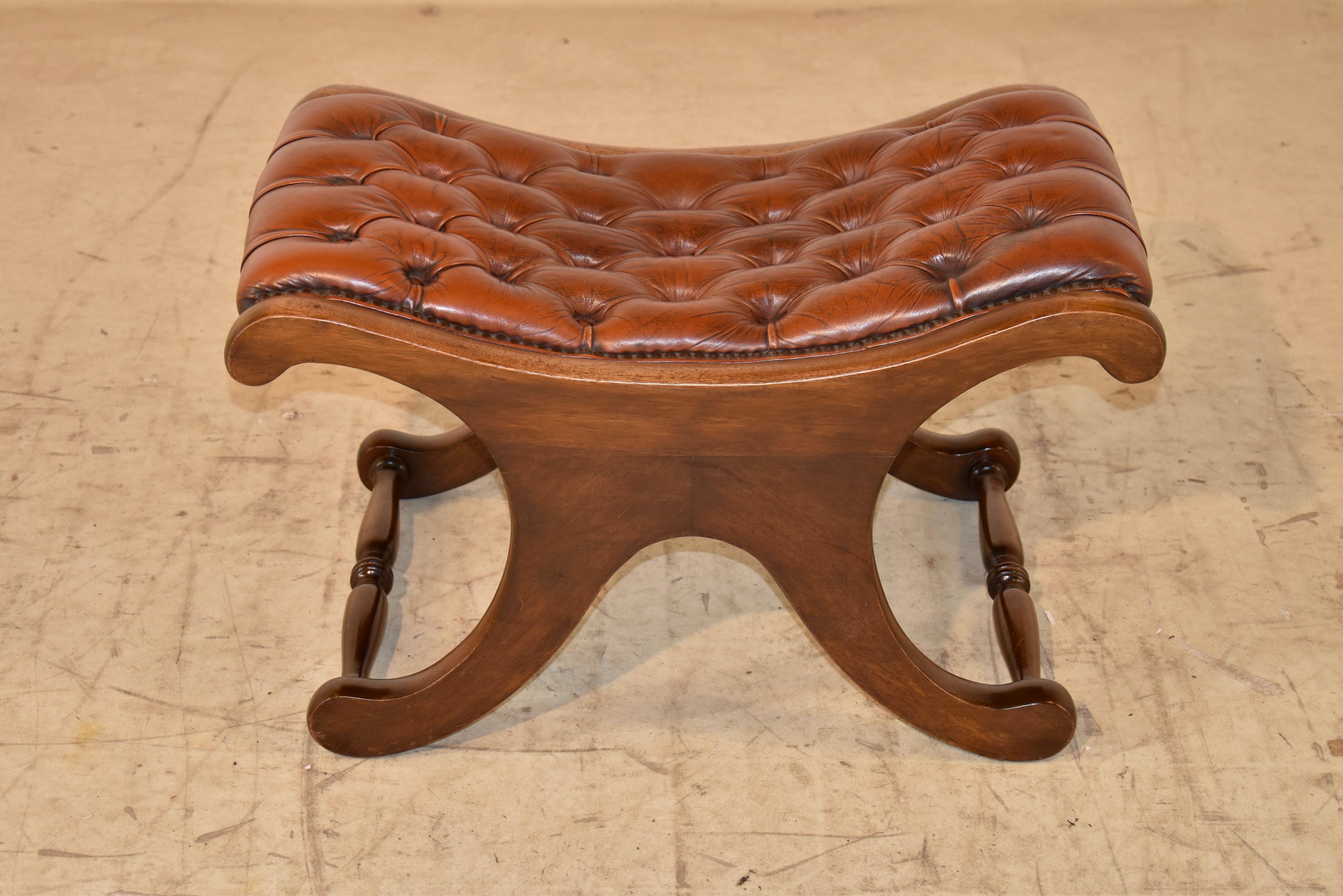 Circa 1900-1920 mahogany stool from England with a brown leather seat. The leather is original and is upholstered in an attractive Chesterfield pattern. The frame is lovely and shapely, with an x type stretcher base. The legs are joined by hand
