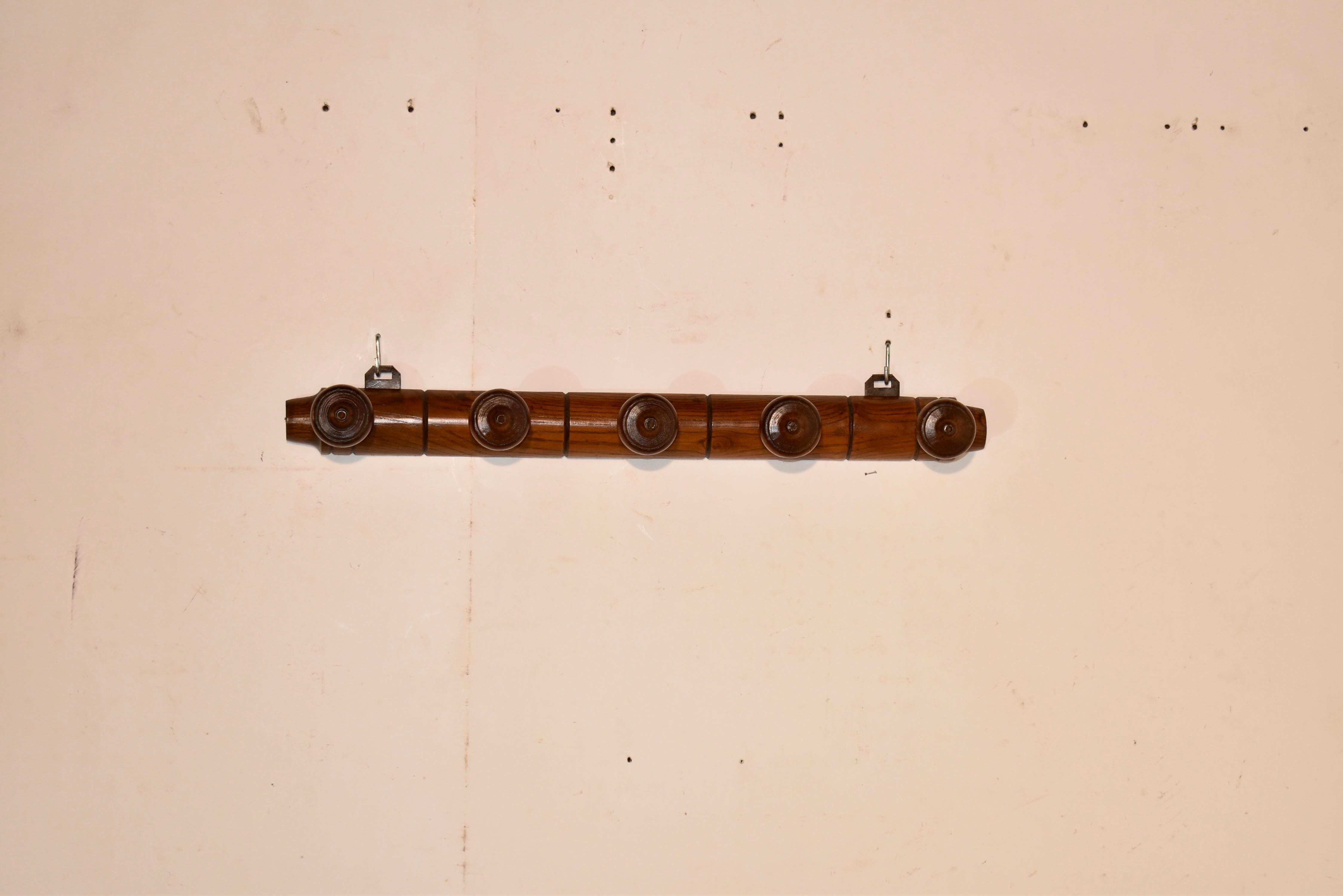 Porta lecca-lecca in olmo del 1920 circa, proveniente dalla Francia.  Il retro è tornito a mano con decorazioni intagliate e dispone di cinque pioli per appendere cappotti o cappelli.  I pioli sono torniti a mano per aggiungere interesse al design. 