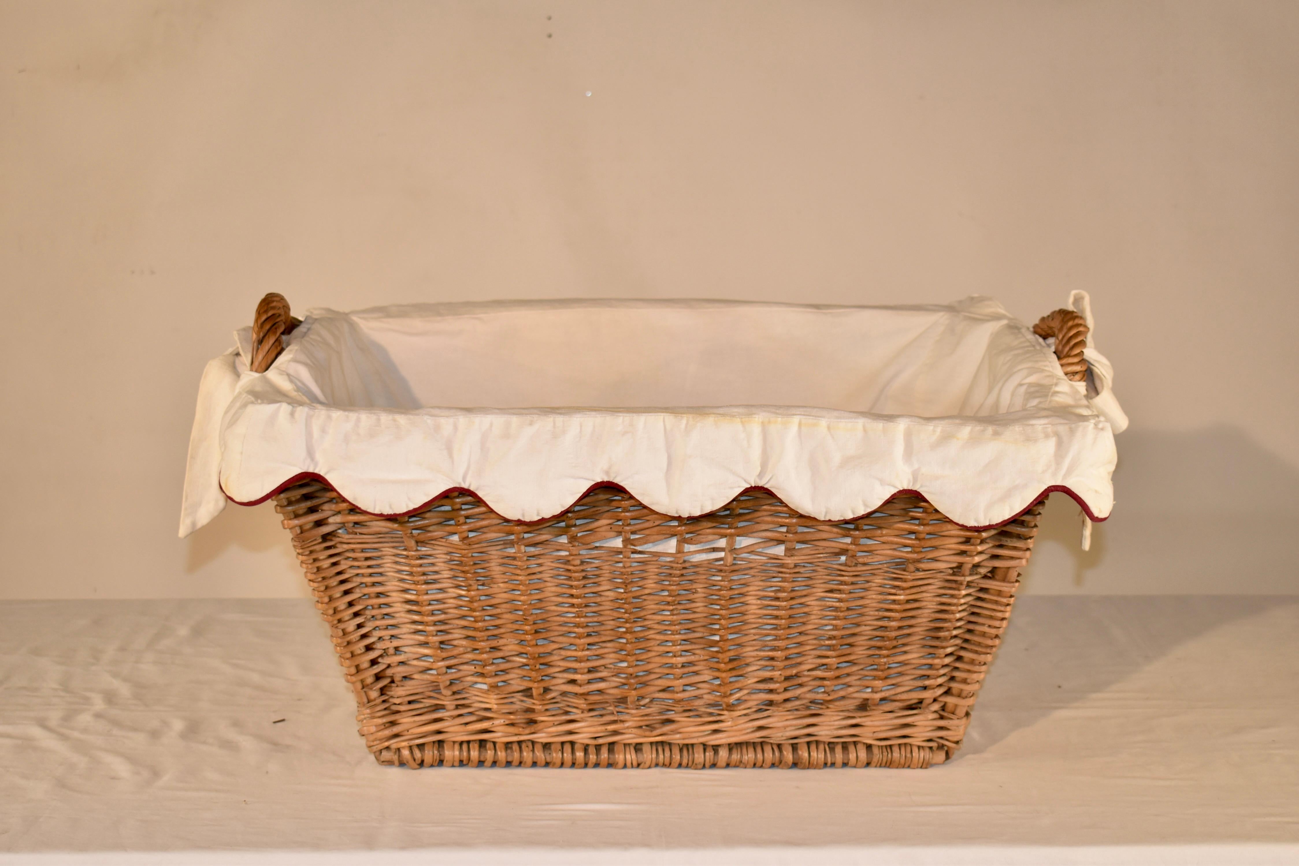 Circa 1920 wicker laundry basket from France with a hand made linen basket liner with burgundy welting.  The liner ties around the handles of the basket.  Great look for any room of the house or office!