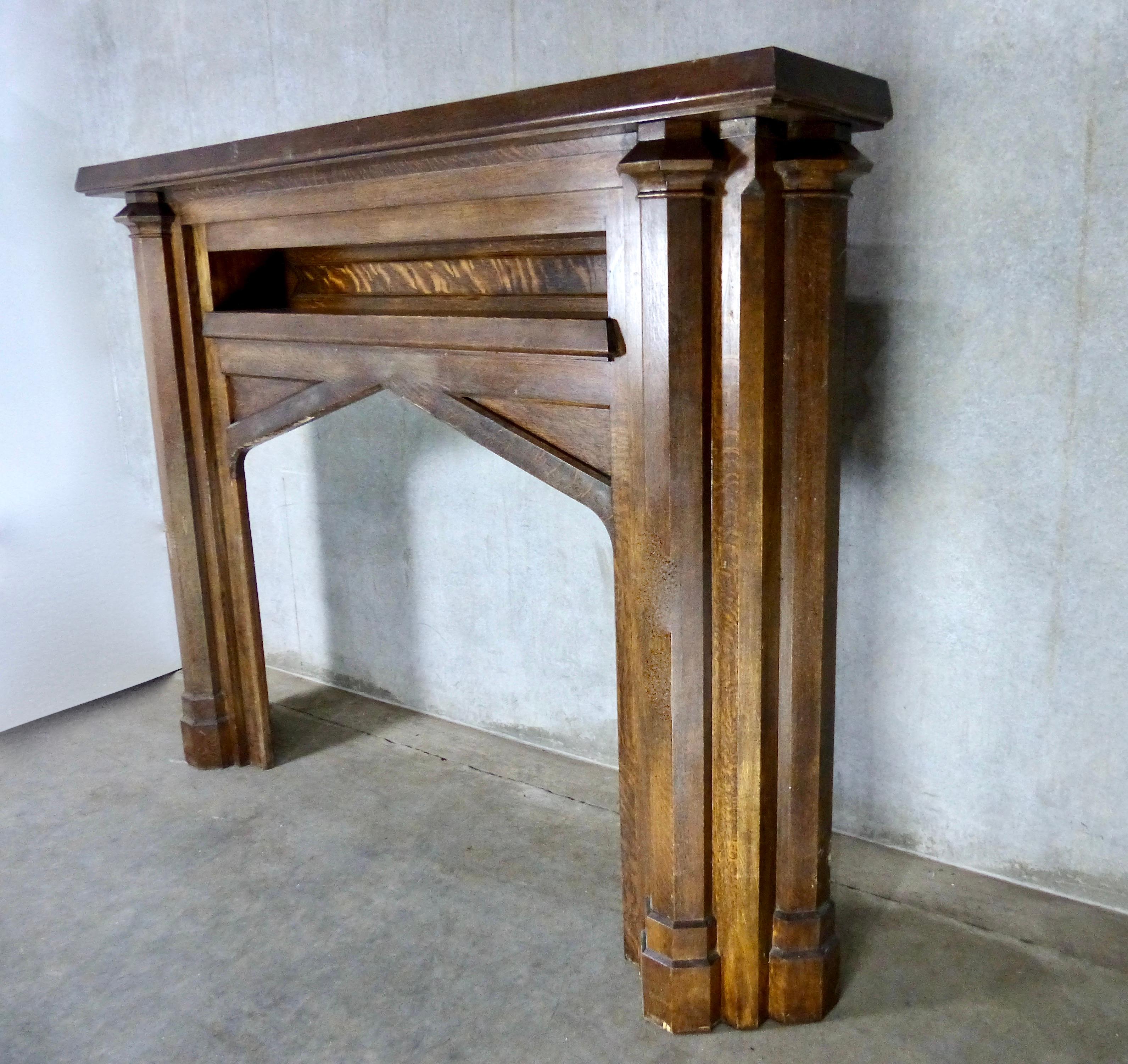 A monumental, solid oak fireplace mantel/surround salvaged from a mansion in Vancouver. Arts & Crafts/Tudor style, and in its original state, it features a small inset shelf, nicely sculpted and capped pillars, and an interior peak. This is a