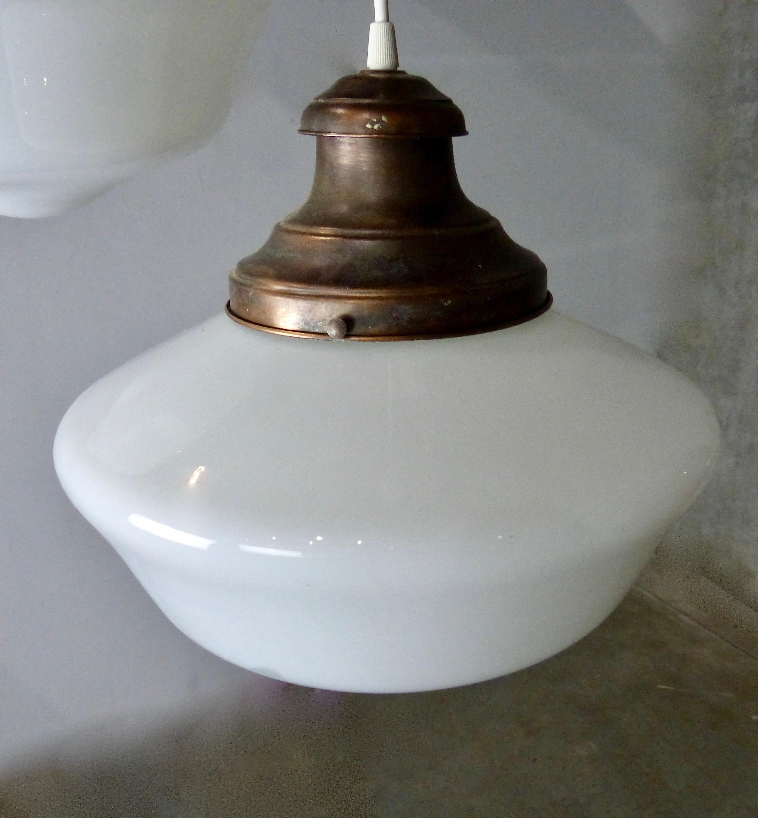 Set of three authentic copper and milk glass, schoolhouse style pendant lights from the 1920s. Original copper fitters. Re-wired and CSA approved to current electrical standards, ceiling mounting plate included. A popular look in modern farmhouse