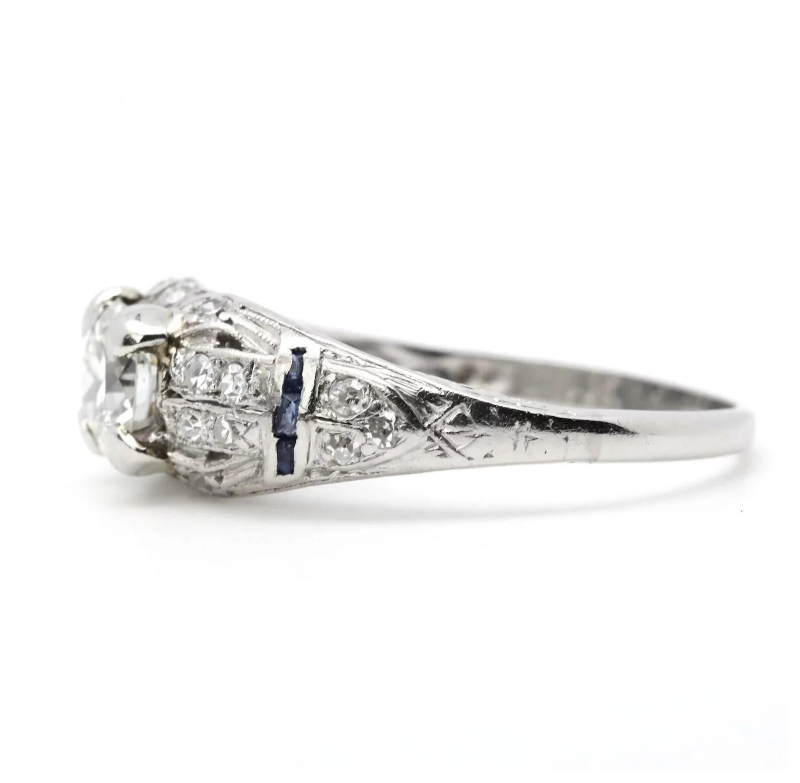 A handmade circa 1920's Art Deco period diamond and sapphire engagement ring in platinum. Centering this ring is a 0.70 carat G color SI1 clarity antique European cut diamond. Framing the center diamond are 22 pave set accenting diamonds and six