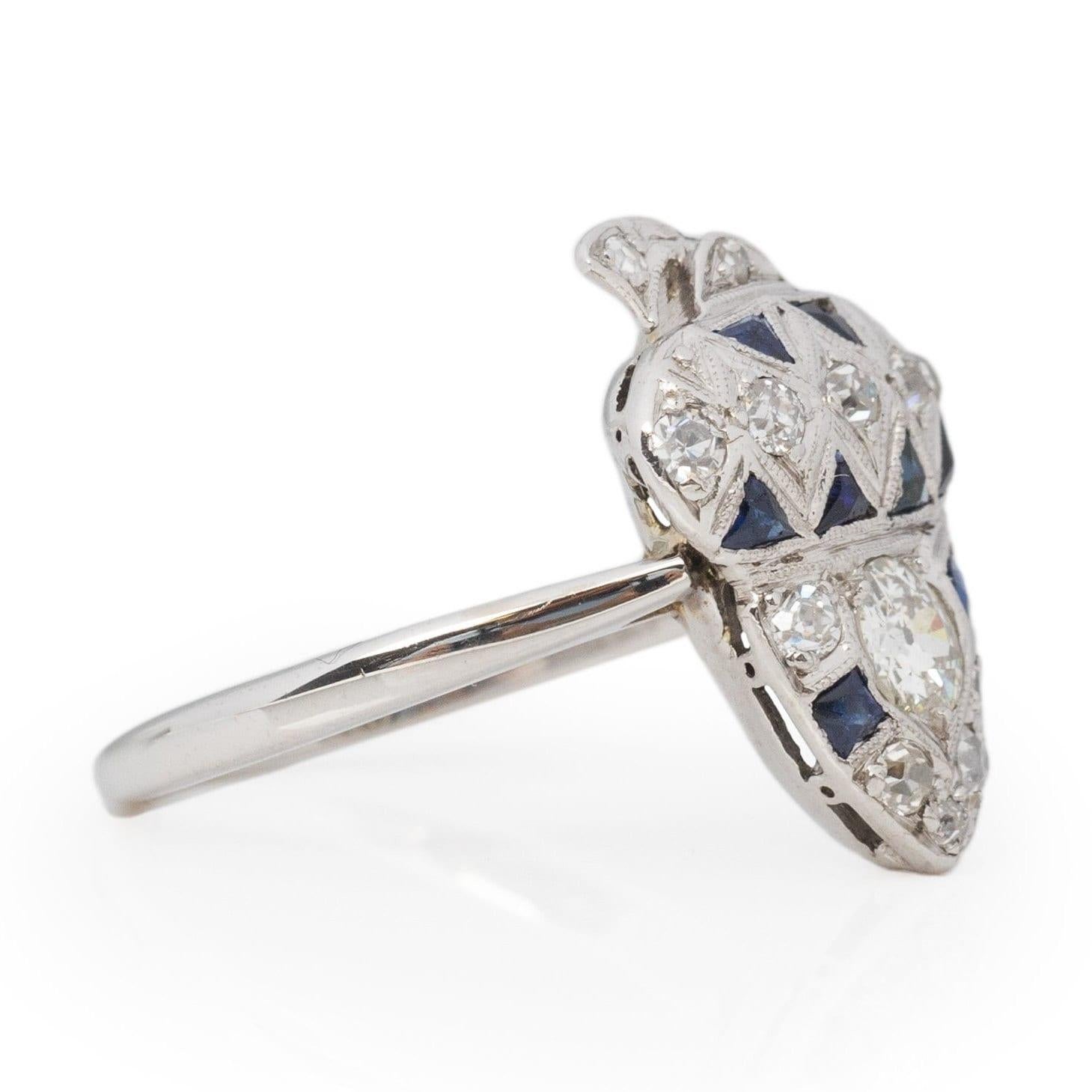 This extraordinary treasure exudes an enchanting charm. Meticulously fashioned from 14K white gold, the understated yet timeless band cradles a dazzling acorn embellished with an array of glistening gemstones. At its core lies a magnificent old