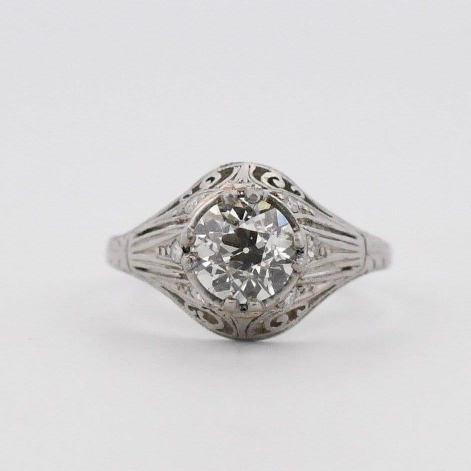 Here we have a stunning Art Deco ring that has captivating design details. The open filigree details flow through the ring holding the center gem, displaying it with ease. Placed throughout the filigree are petit single cut diamonds giving the ring