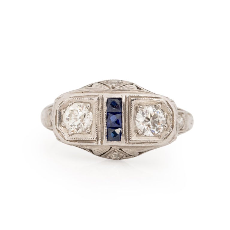 This little art deco beauty, looks small but packs punch with all its carved details. Crafted in platinum, the gallery has outstanding carved filigree details, that wined and flow down the shanks. All accented by small diamonds on the tops of the