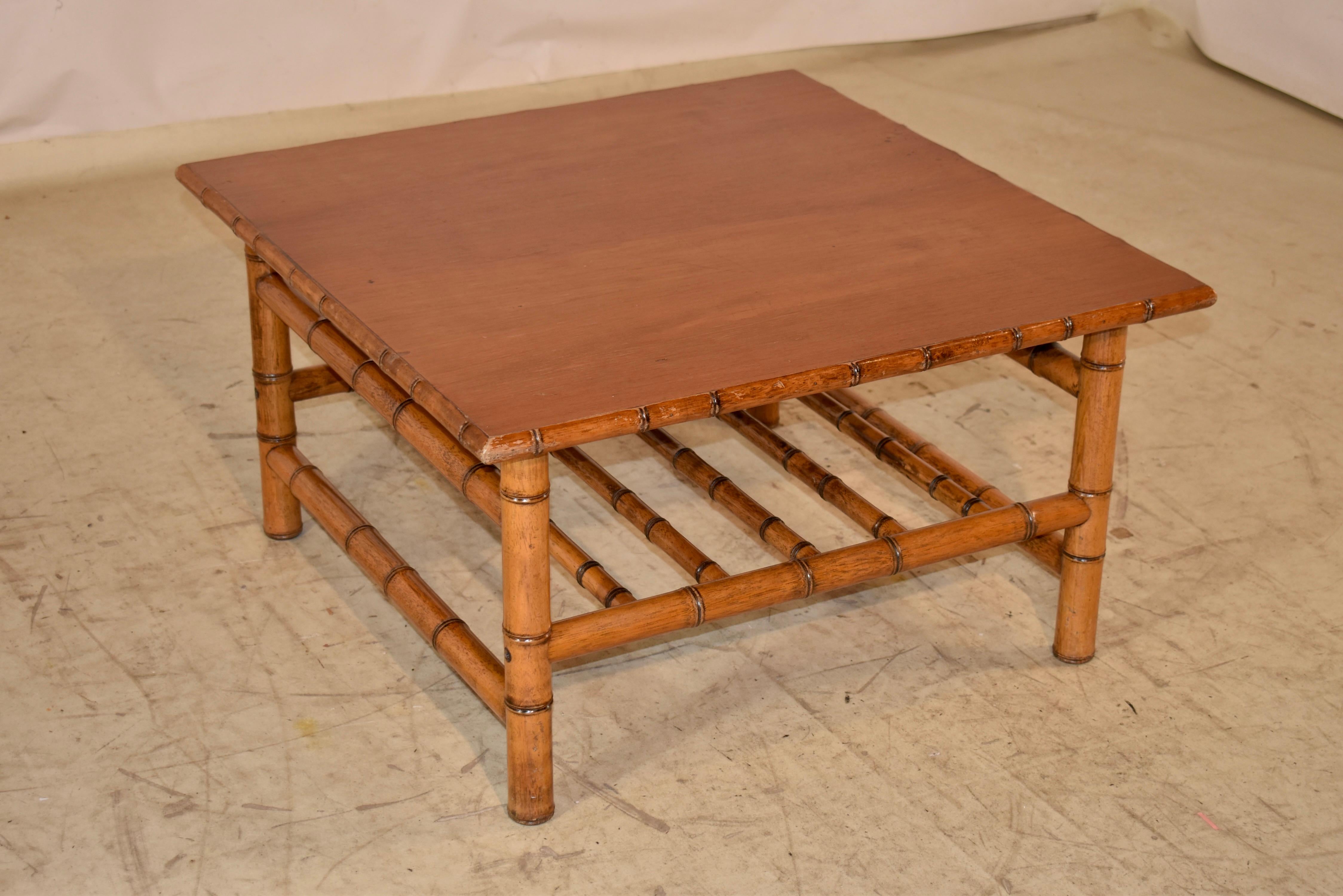 Mesa de centro francesa de imitación de bambú de los años 20 hecha de cerezo.  La parte superior está hecha de  cerezo y la parte superior está ribeteada con molduras torneadas de imitación de bambú.  La mesa se apoya en patas de bambú de imitación