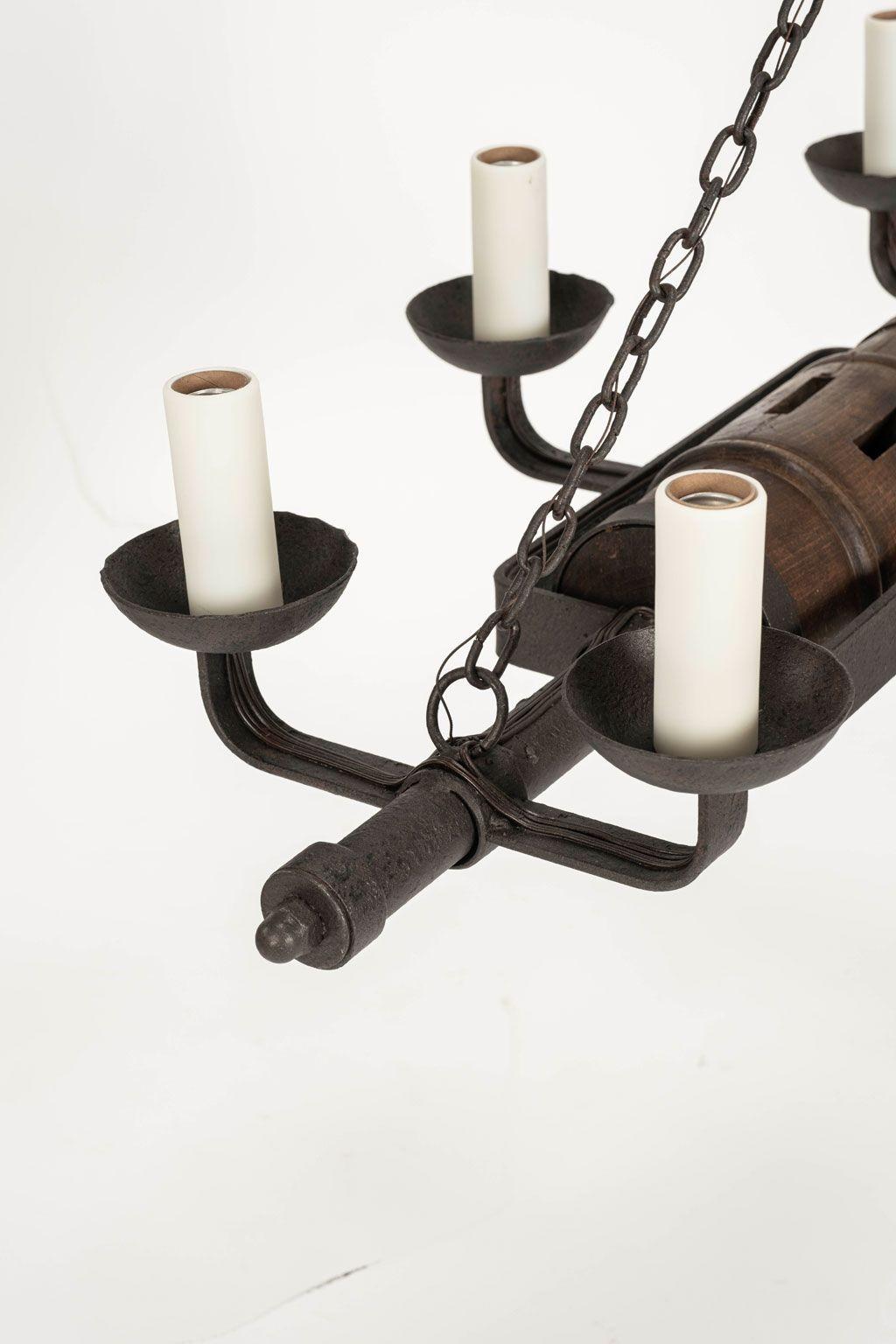 Circa 1930-1959 rustic French iron and wooden chandelier, newly-wired for use within the USA. Circa 1880s wooden wagon axle housed within a vintage iron frame. Newly-wired for use within the USA with six medium-base size sockets. Iron frame