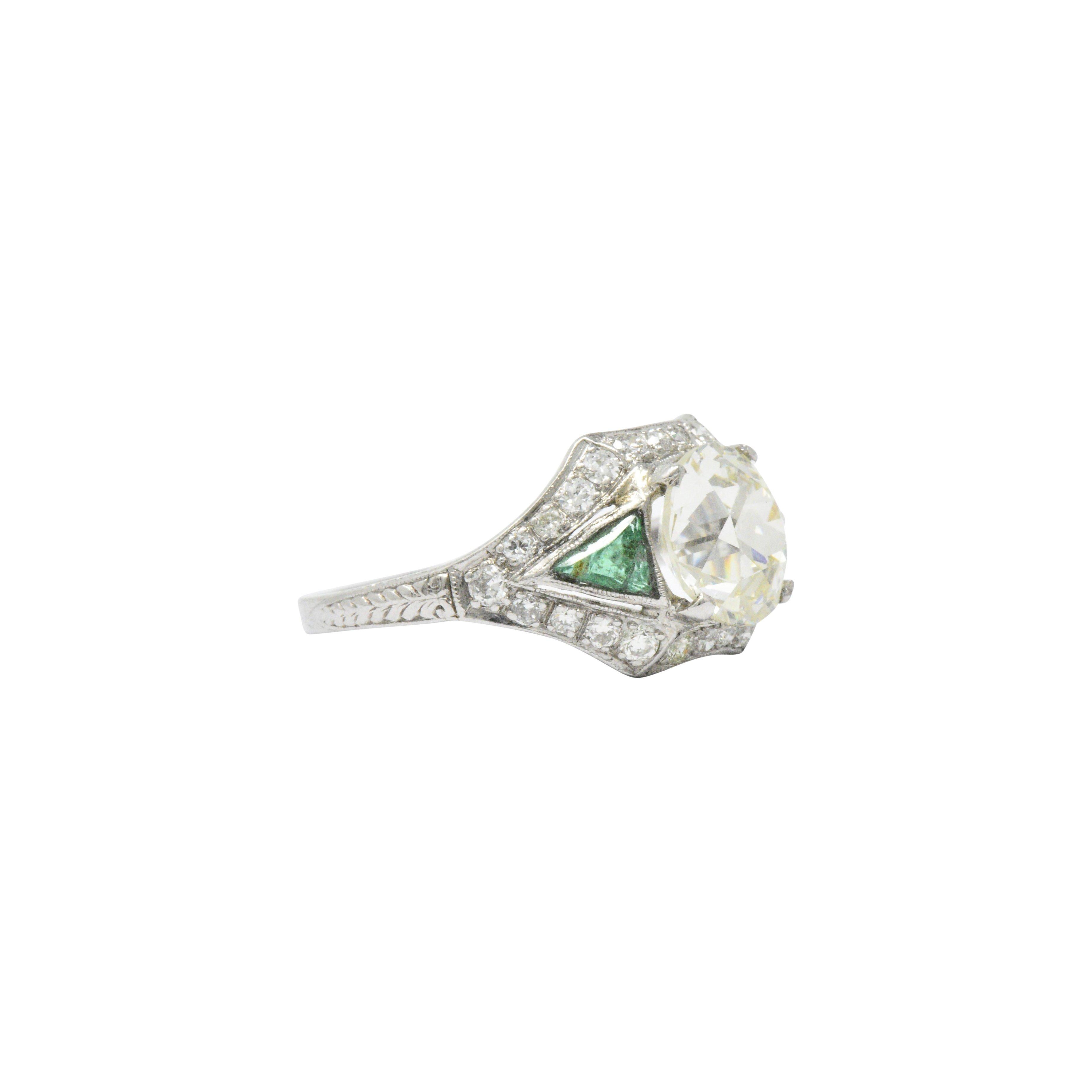Centering an old European cut diamond weighing 2.71 carat, N color and VS1 clarity

Symmetrical setting containing 26 transitional cut diamonds weighing approximately .40 carats total weight

Two triangular faceted natural emerald accents weighing