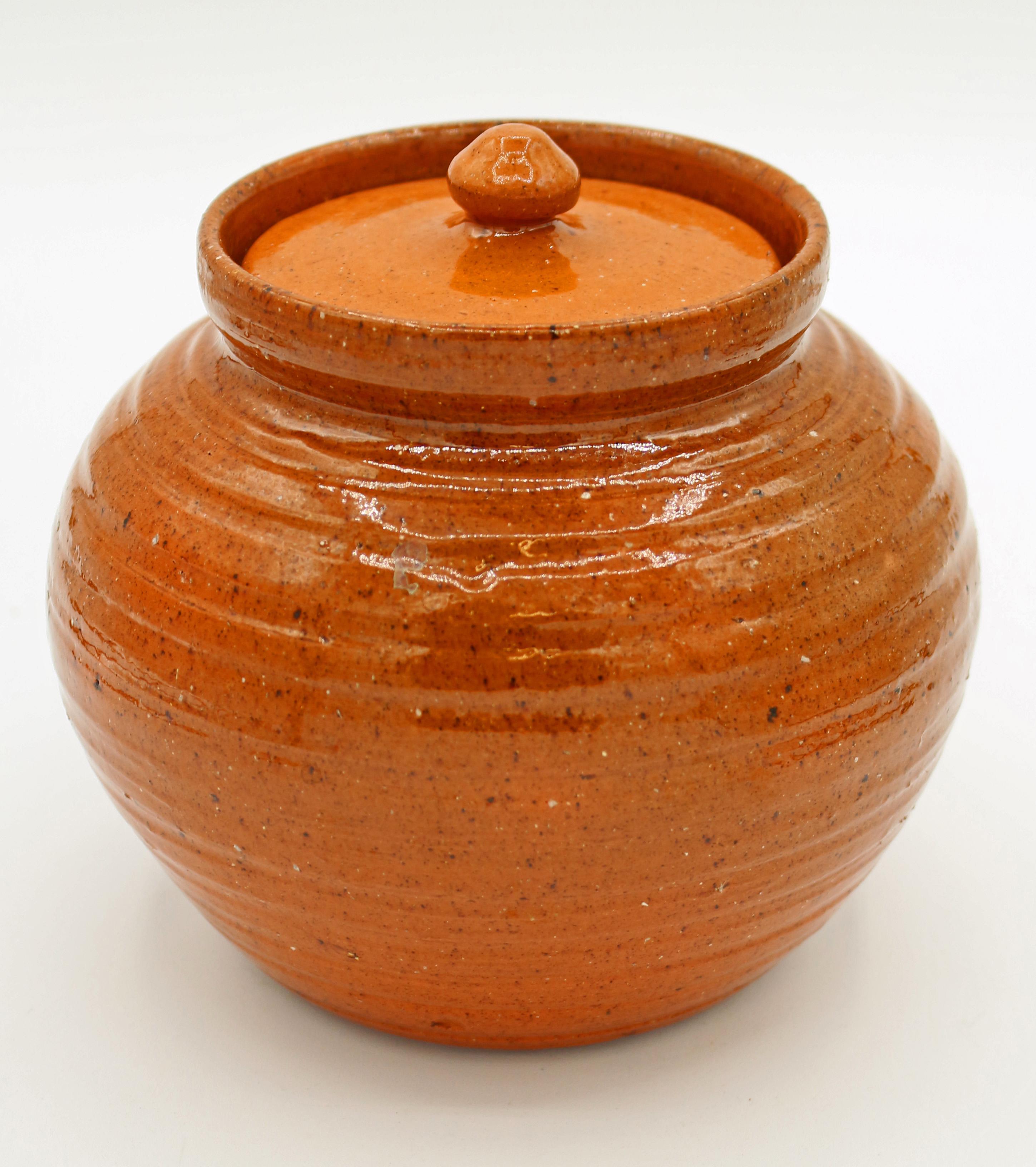 c. 1930-50s covered pottery pot by Ben Owen I, 1st Jugtown mark. The turning lines are elegant. Orange glazes. The cover is a perfect fit, even if lighter in color. Provenance: Tranquil Corners Antiques and found in CT; collection of Katherine Reid,