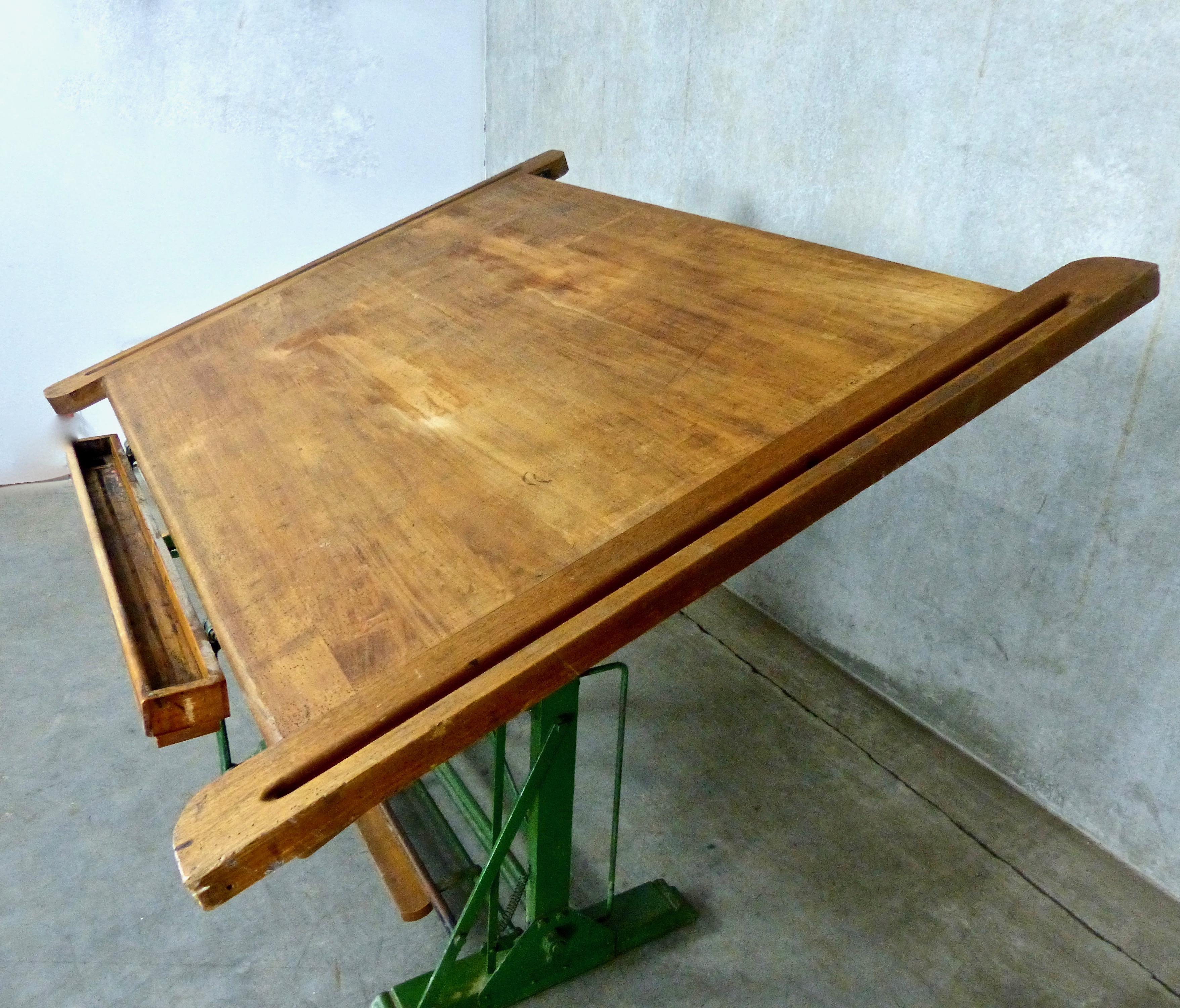A fully adjustable wooden drafting table with a cast iron base. Made in the 1930s by Kahn Freres of Bruxelles, an office furniture design firm. Beautiful patina on its oak wood top, which also features a separate pencil case in pine. Hard-to-find