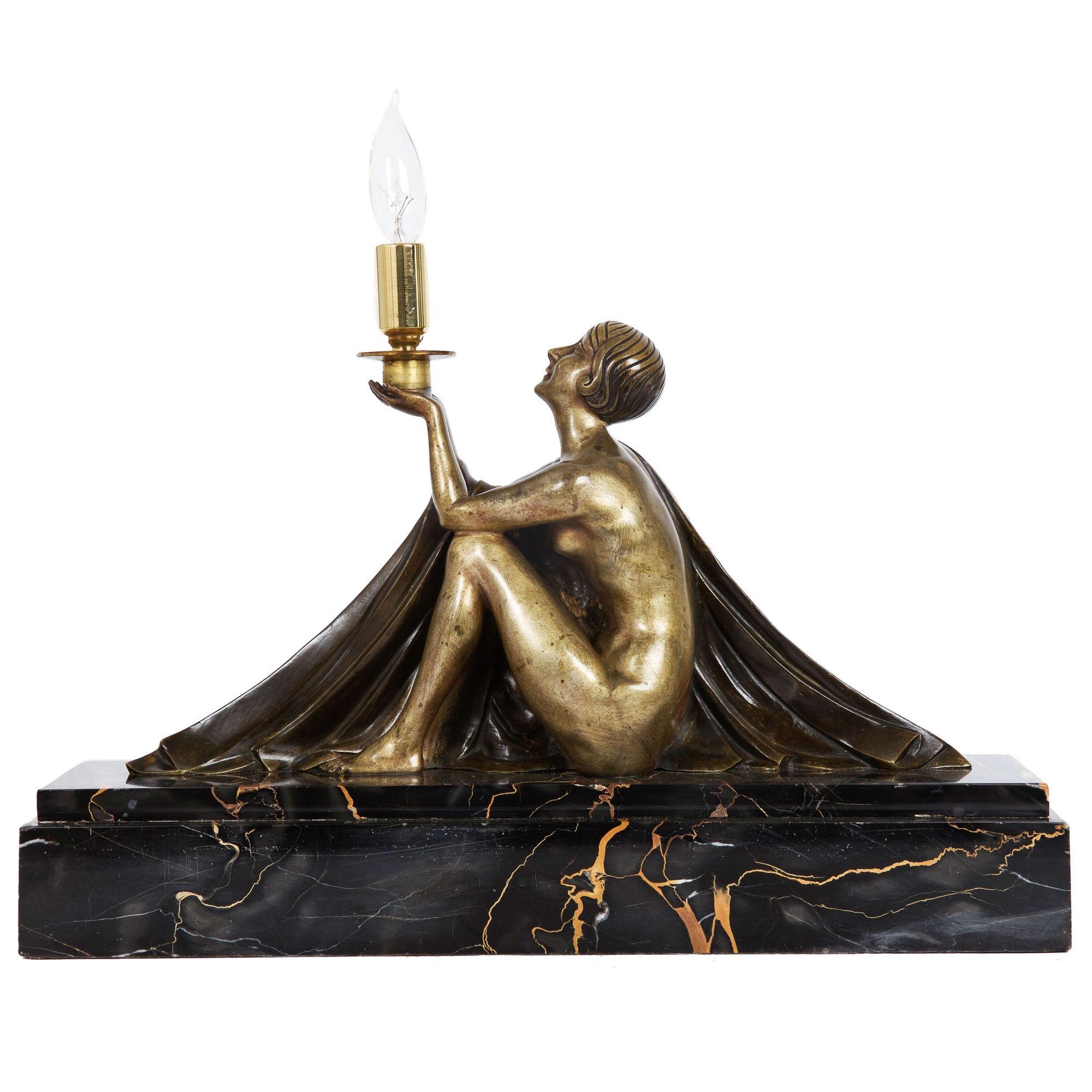 JEAN LORMIER
Französisch, 20. Jahrhundert

Figurale Lampe einer Frau, die eine Lampe hält

Figur aus patinierter Bronze, Kerzenständer aus Messing, Sockel aus Marmor  Verso signiert 