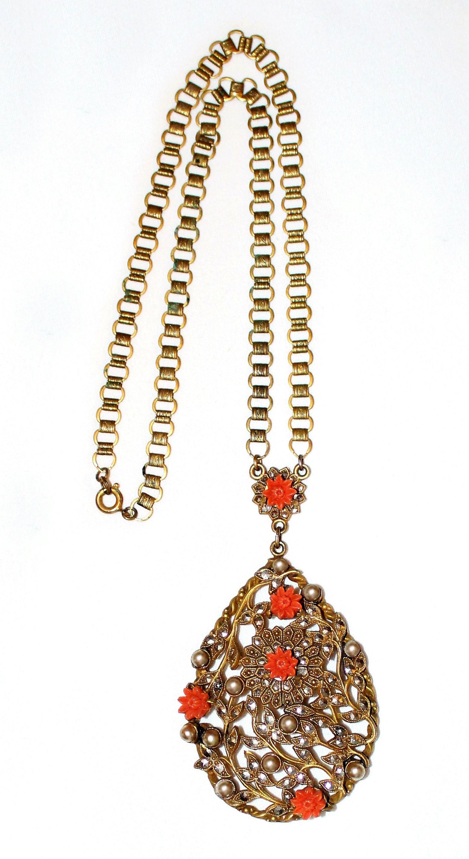 Circa 1930 goldtone metal book-chain necklace with a large floral motif pendant.  This ornately designed pendent is set with marcasite, faux-pearls and is embellished with coral celluloid flowers.  The necklace measures 19