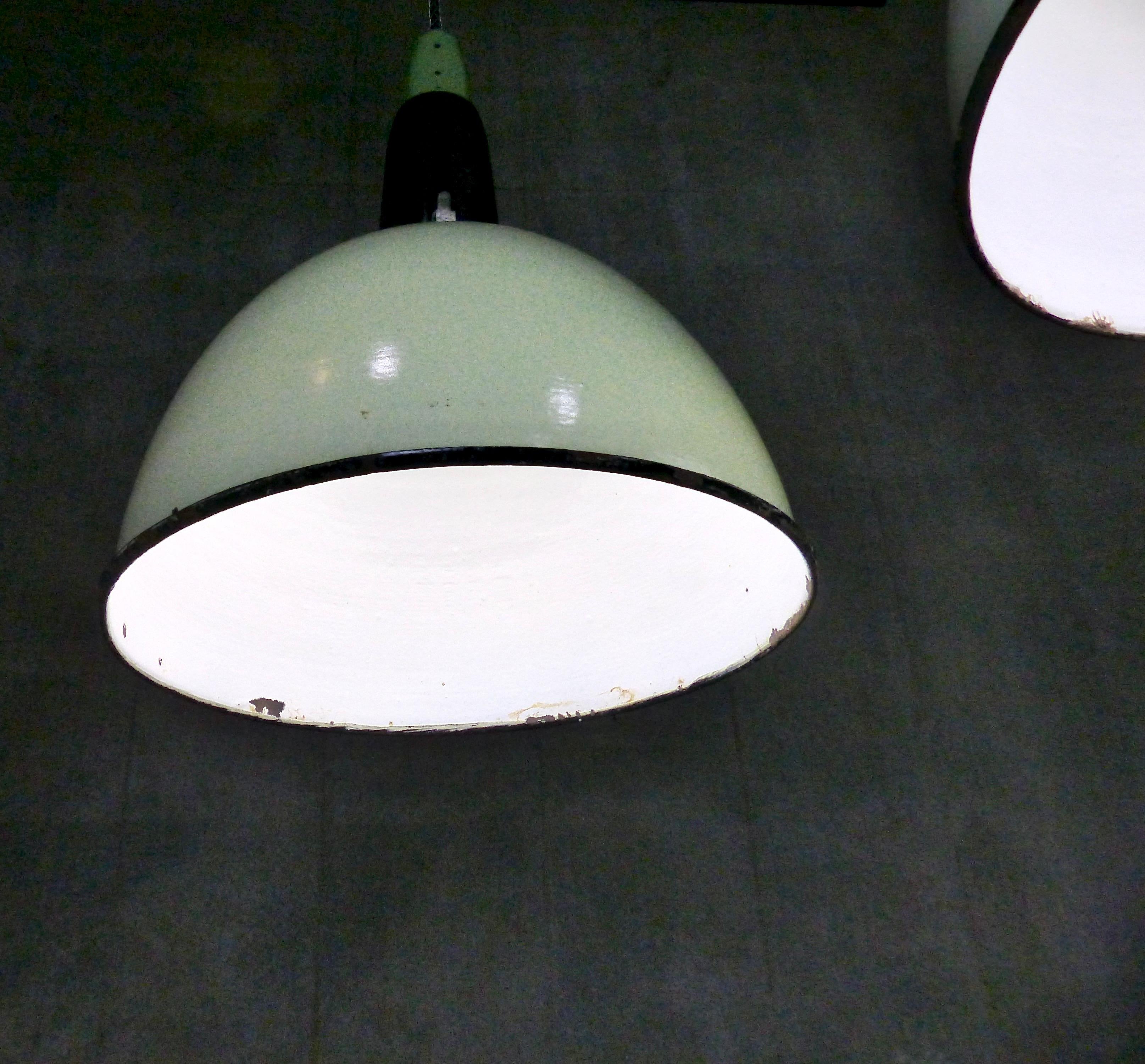 Very cool and unusual vintage industrial pendant lights from Europe. Original circa 1930s pale green enamel-over-metal shades with black-and-green caps. We currently have 12 in stock. Re-wired and inspected and approved to current electrical