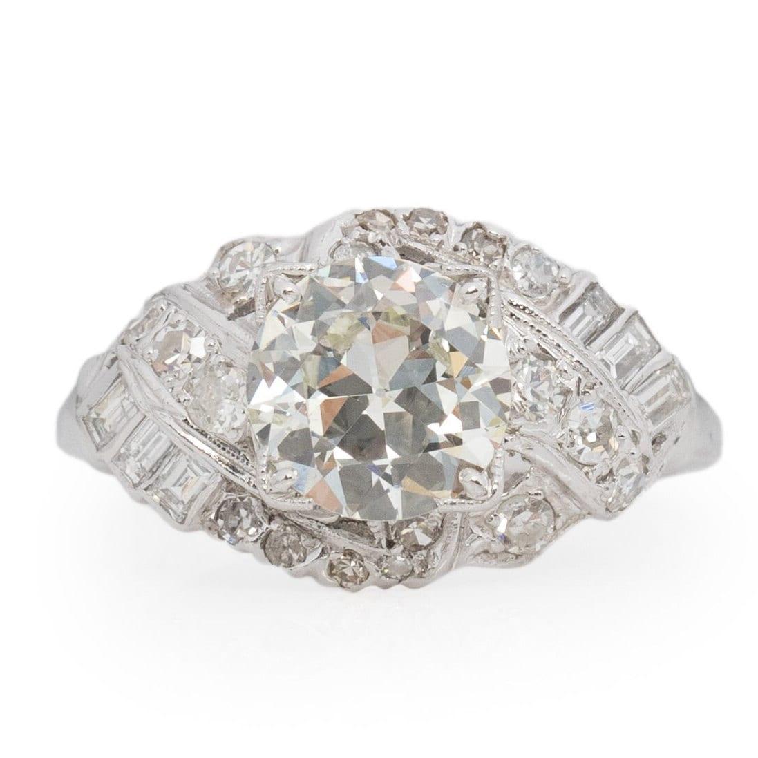 Overflowing with Art Deco allure, this platinum ring features a stunning Old European Cut center diamond, complemented by over a dozen baguette and single-cut diamonds. The smooth, straight shanks ensure comfortable wear, while a dazzling wave of