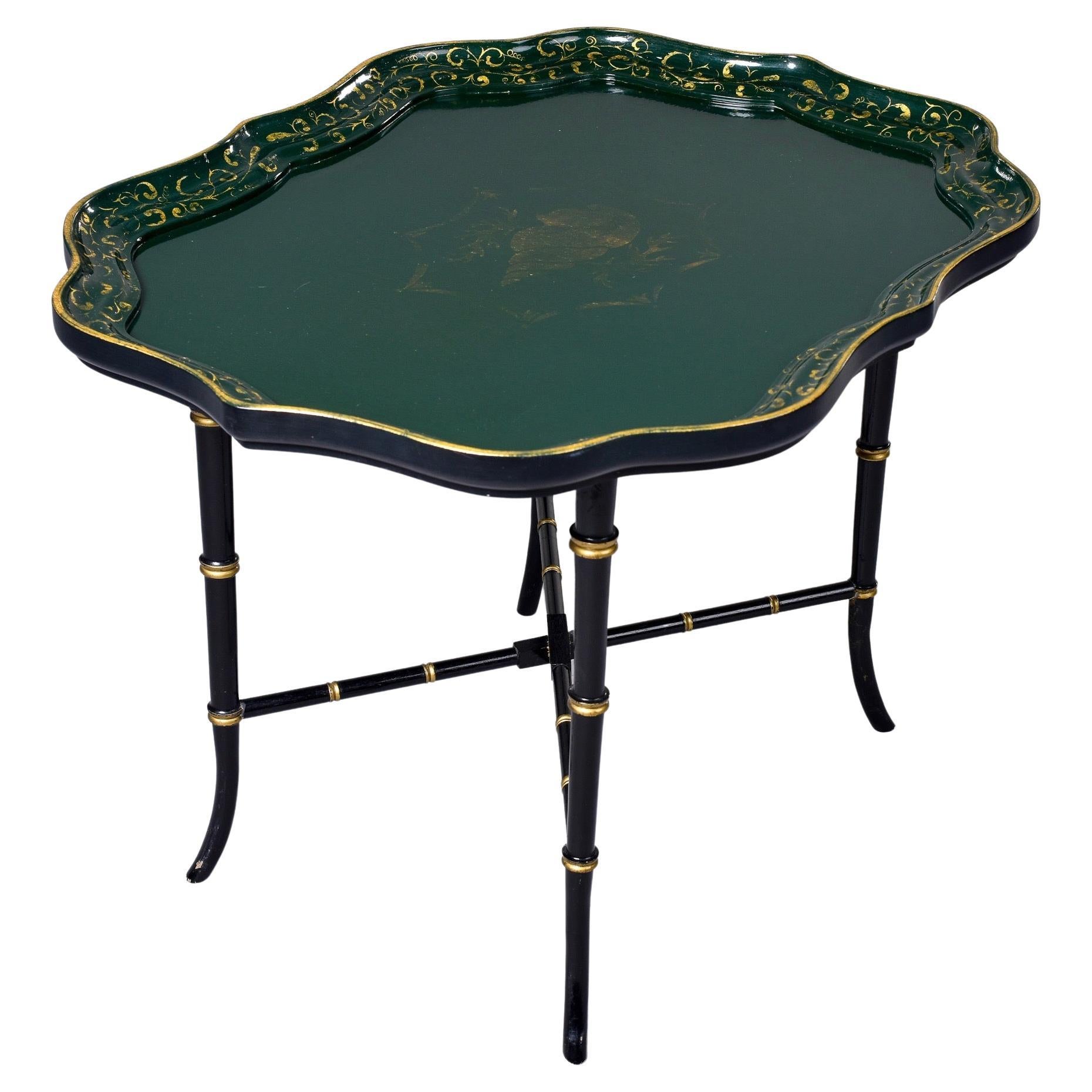 Found in England, this circa 1930s tray top table has a black and gilded faux bamboo base with an X-form stretcher. Removable tray top has a deep green painted finish with gilded painted details including a shell and seaweed vines. Unknown maker.