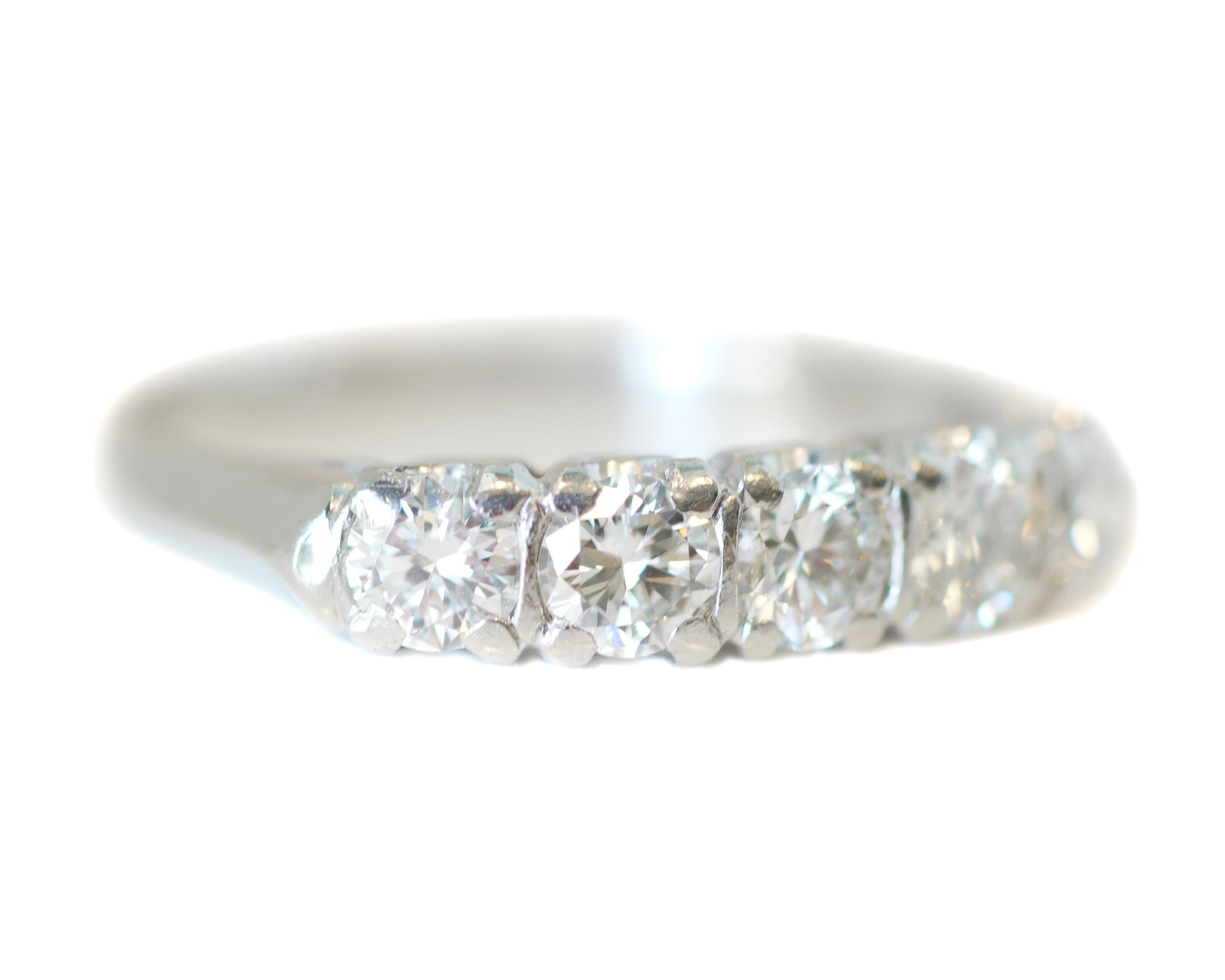 Item Description:
This band is sparkling with a total of 5 diamonds along the front frame. The transition cut diamonds total to 1.00 ct. The stones are embedded in bezel frames with the sides visible underneath the U-shaped prongs. The shiny frame