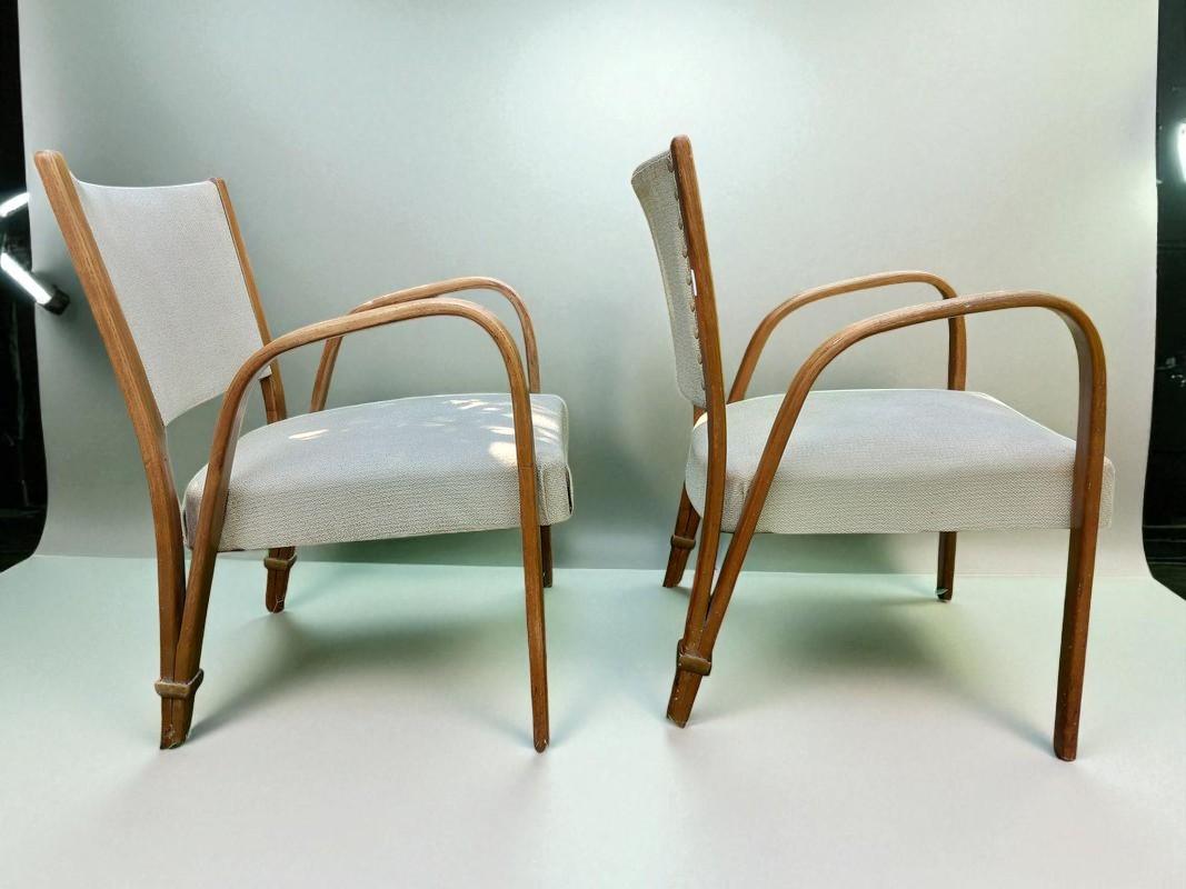 This elegant pair of mid-century modern lounge chairs showcases the refined craftsmanship of French maker Bow-Wood, active in Villeneuve-Saint-Georges. Defined by their gracefully curved bentwood arms and legs, the chairs offer a harmonious balance