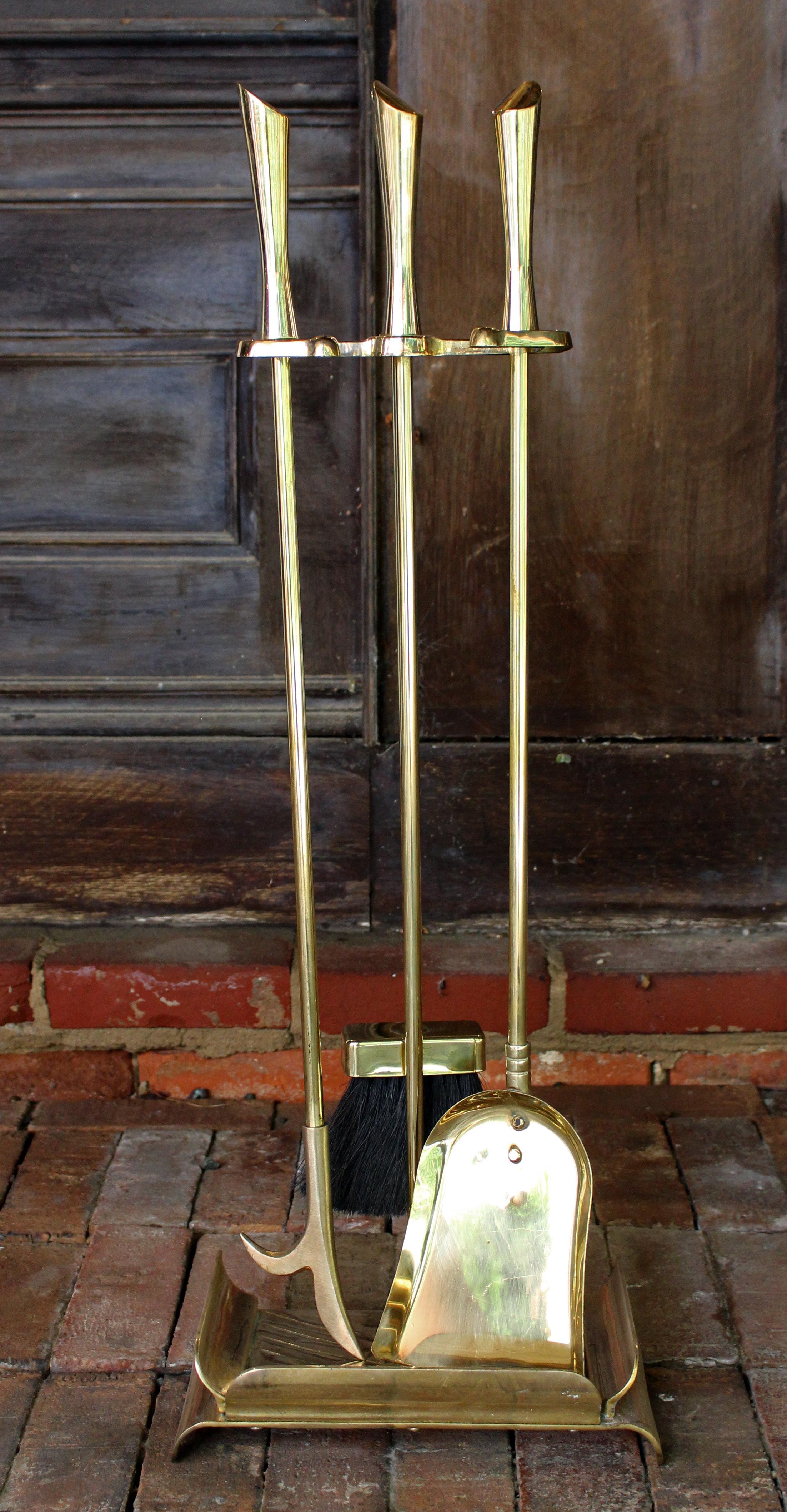 Circa 1950s brass fireplace set with original stand. Sculptural mid century modern set - shovel, poker & brush. Very heavy. Newly professionally polished. Stand: 31 1/2